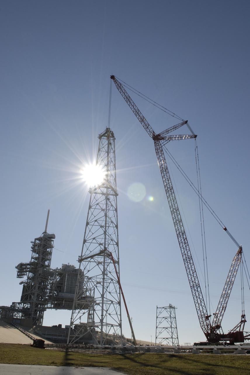 CAPE CANAVERAL, Fla. –   Brilliant beams of sunlight bounce off the new lightning tower under construction on Launch Pad 39B at NASA's Kennedy Space Center in Florida.  New sections are being added with the help of a giant crane (at right). Three new lightning towers on the pad will be 500 feet tall with an additional 100-foot fiberglass mast atop supporting a wire catenary system.  Pad 39B will be the site of the first Ares vehicle launch, including the Ares I-X test flight that is targeted for July 2009. This improved lightning protection system allows for the taller height of the Ares I rocket compared to the space shuttle.  Photo credit: NASA/Kim Shiflett