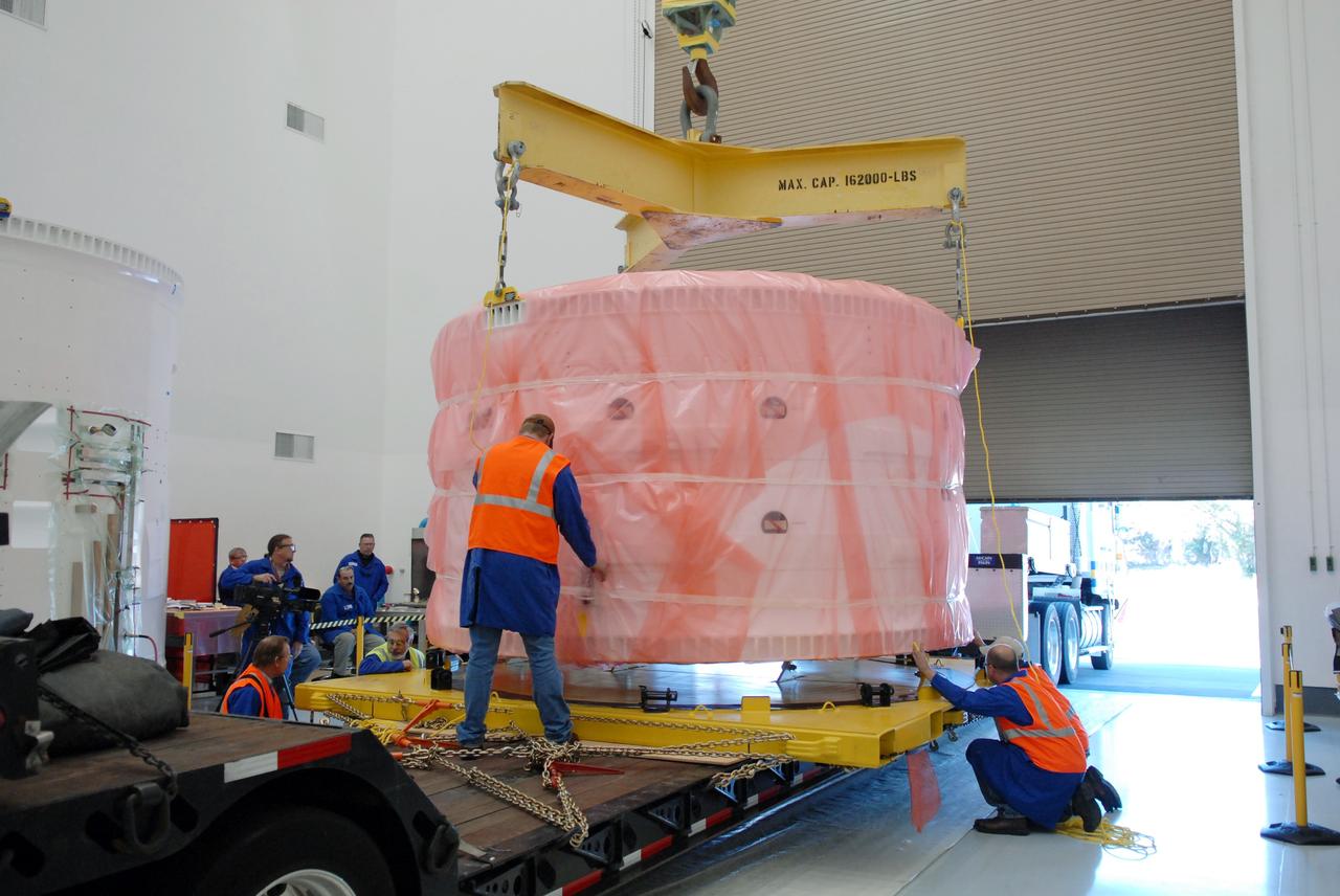 CAPE CANAVERAL, Fla. – At Astrotech in Titusville, Fla., the Ares I-X forward skirt, wrapped in a protective cover, is lowered by crane onto a transporter. The segment will be transferred to the Assembly and Refurbishment Facility, or ARF, at NASA's Kennedy Space Center in Florida. The forward skirt is the initial piece of first-stage hardware in preparation for the July 2009 test flight of the agency's next-generation spacecraft and launch vehicle system. Built entirely of armored steel, the 14,000-pound segment is seven feet tall and 12-1/4 feet wide. United Space Alliance, under a subcontract to ATK, will complete the integration and assembly of the forward skirt components in the ARF. It will then be moved to the Vehicle Assembly Building high bay 3 for stacking operations. Photo credit: NASA/Tim Jacobs
