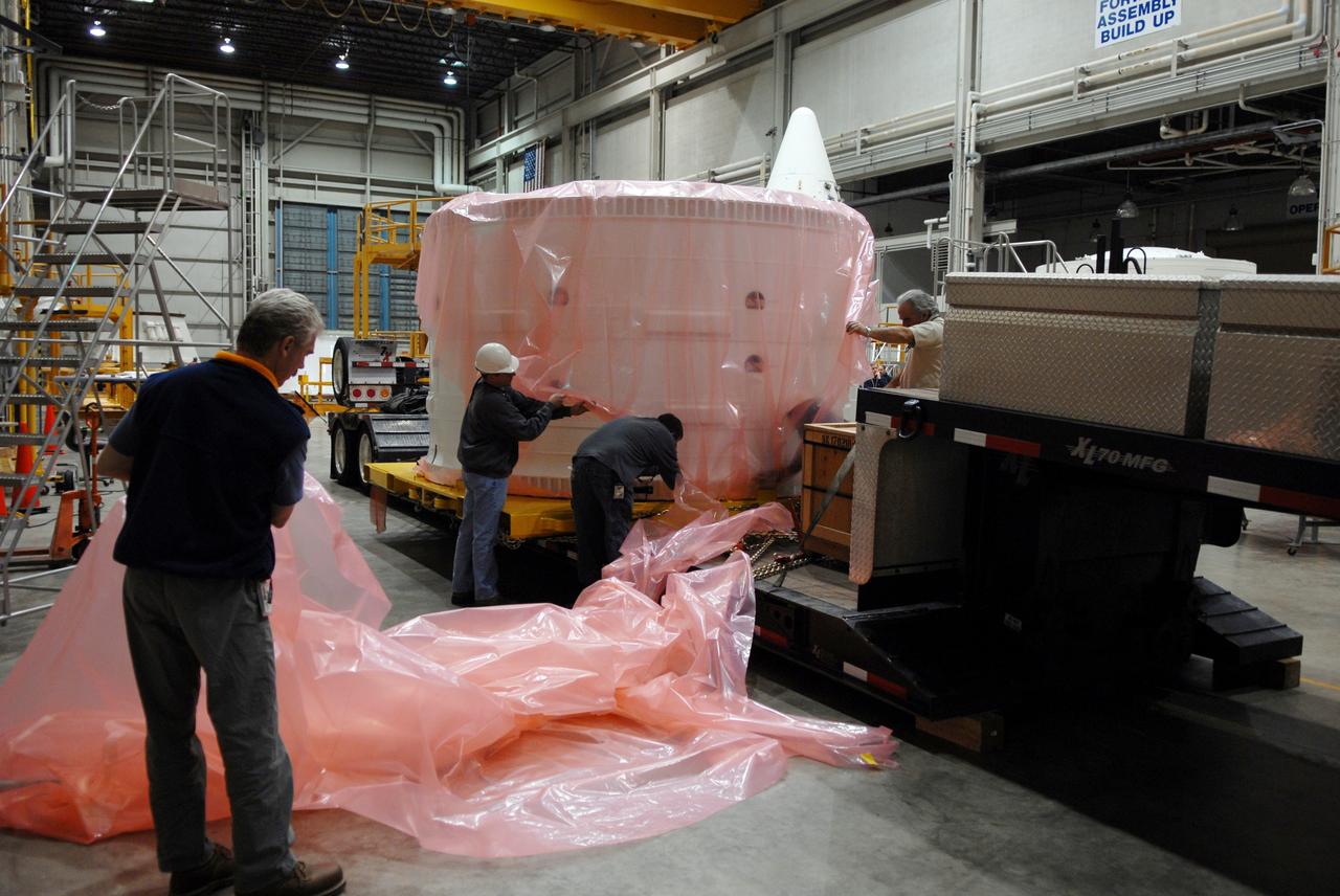 CAPE CANAVERAL, Fla. – Inside the Assembly and Refurbishment Facility, or ARF, at NASA's Kennedy Space Center in Florida, workers begin removing the protective cover from around the Ares I-X forward skirt. The forward skirt is the initial piece of first-stage hardware in preparation for the July 2009 test flight of the agency's next-generation spacecraft and launch vehicle system. Built entirely of armored steel, the 14,000-pound segment is seven feet tall and 12-1/4 feet wide. United Space Alliance, under a subcontract to ATK, will complete the integration and assembly of the forward skirt components in the ARF. It will then be moved to the Vehicle Assembly Building high bay 3 for stacking operations. Photo credit: NASA/Tim Jacobs