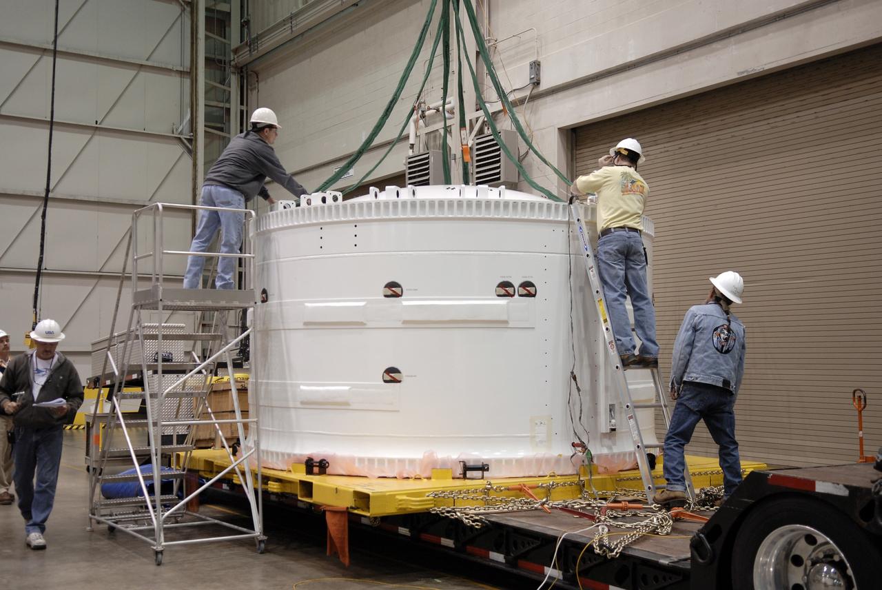 CAPE CANAVERAL, Fla. –    Inside the Assembly and Refurbishment Facility at NASA's Kennedy Space Center in Florida, workers attach cables to the Ares I-X forward skirt, which was transported from the Astrotech facility.  The segment will be lifted off the transporter and placed on supports on the floor.  United Space Alliance, under a subcontract to ATK, will complete the integration and assembly of the forward skirt components in the ARF. It will then be moved to the Vehicle Assembly Building high bay 3 for stacking operations. The forward skirt is the initial piece of first-stage hardware in preparation for the July 2009 test flight of the agency's next-generation spacecraft and launch vehicle system. Built entirely of armored steel, the 14,000-pound segment is seven feet tall and 12-1/4 feet wide.  Photo credit: NASA/Kim Shiflett