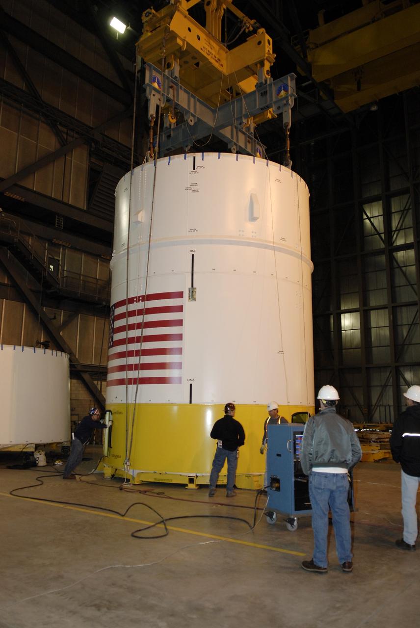 CAPE CANAVERAL, Fla. – In high bay 4 of the Vehicle Assembly Building at NASA's Kennedy Space Center in Florida, an overhead crane is attached to segments 6 and 7 of the Ares I-X rocket. The segments are being moved onto a stand on the floor. Ares I-X is the test vehicle for the Ares I, which is part of the Constellation Program to return men to the moon and beyond. Ares I is the essential core of a safe, reliable, cost-effective space transportation system that eventually will carry crewed missions back to the moon, on to Mars and out into the solar system. Ares I may also use its 25-ton payload capacity to deliver resources and supplies to the International Space Station, or to "park" payloads in orbit for retrieval by other spacecraft bound for the moon or other destinations. The Ares I-X is targeted for launch in July 2009. Photo credit: NASA/Kim Shiflett
