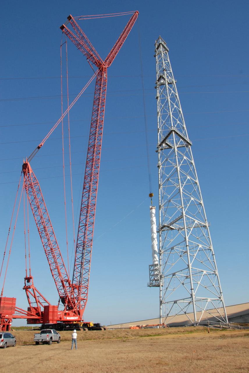 CAPE CANAVERAL, Fla. –  On Launch Pad 39B at NASA's Kennedy Space Center in Florida, a crane begins lifting a 100-foot fiberglass lightning mast to place it on top of one of the 500-foot towers being constructed for the Constellation Program and Ares/Orion launches. This improved lightning protection system allows for the taller height of the Ares I rocket compared to the space shuttle.  Pad 39B will be the site of the first Ares vehicle launch, including the Ares I-X test flight that is targeted for July 2009.