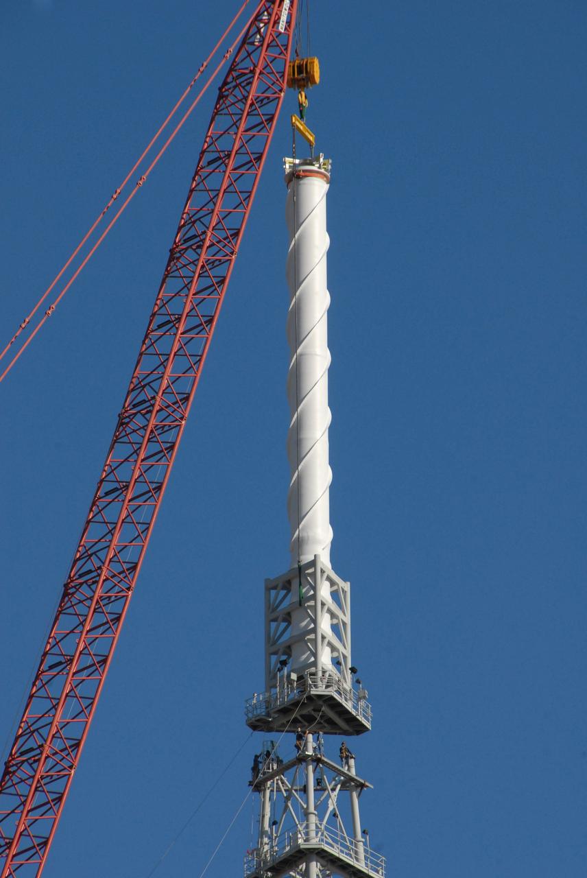 CAPE CANAVERAL, Fla. –  On Launch Pad 39B at NASA's Kennedy Space Center in Florida, a crane places a 100-foot fiberglass lightning mast on top of the 500-foot tower. The tower is one of three being constructed for the Constellation Program and Ares/Orion launches.  This improved lightning protection system allows for the taller height of the Ares I rocket compared to the space shuttle.  Pad 39B will be the site of the first Ares vehicle launch, including the Ares I-X test flight that is targeted for July 2009. Photo credit: NASA/Jack Pfaller