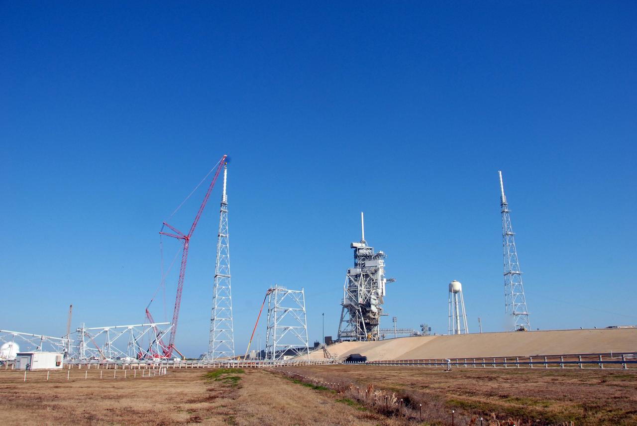 CAPE CANAVERAL, Fla. –  On Launch Pad 39B at NASA's Kennedy Space Center in Florida, a crane places a 100-foot fiberglass lightning mast on top of the 500-foot tower. The tower is one of three being constructed for the Constellation Program and Ares/Orion launches. Another tower is seen at right. This improved lightning protection system allows for the taller height of the Ares I rocket compared to the space shuttle.  Pad 39B will be the site of the first Ares vehicle launch, including the Ares I-X test flight that is targeted for July 2009. Photo credit:  NASA/Jack Pfaller