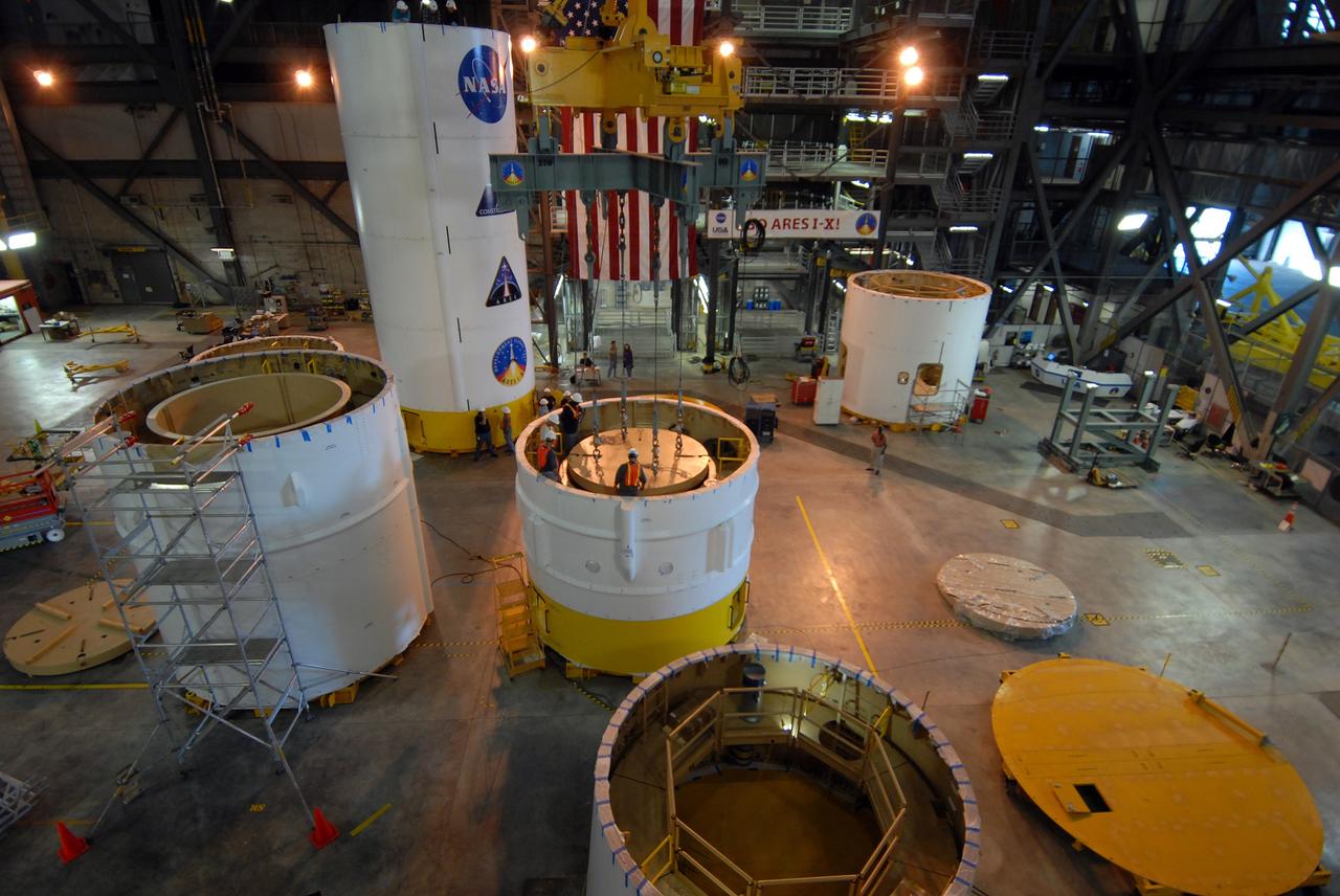 CAPE CANAVERAL, Fla. –  At center, ballast is lowered into segment 7 of the Ares I-X  rocket in Vehicle Assembly Building high bay 4.  Other segments are stacked around the bay.  These ballast assemblies are being installed in the upper stage segments 1 and 7 and will mimic the mass of the fuel. Their total weight is approximately 160,000 pounds.Ares I-X  is the test vehicle for the Ares I, which is part of the Constellation Program to return men to the moon and beyond.  Ares I is the essential core of a safe, reliable, cost-effective space transportation system that eventually will carry crewed missions back to the moon, on to Mars and out into the solar system. The Ares I-X  is targeted for launch in July 2009.  Photo credit: NASA/Jack Pfaller