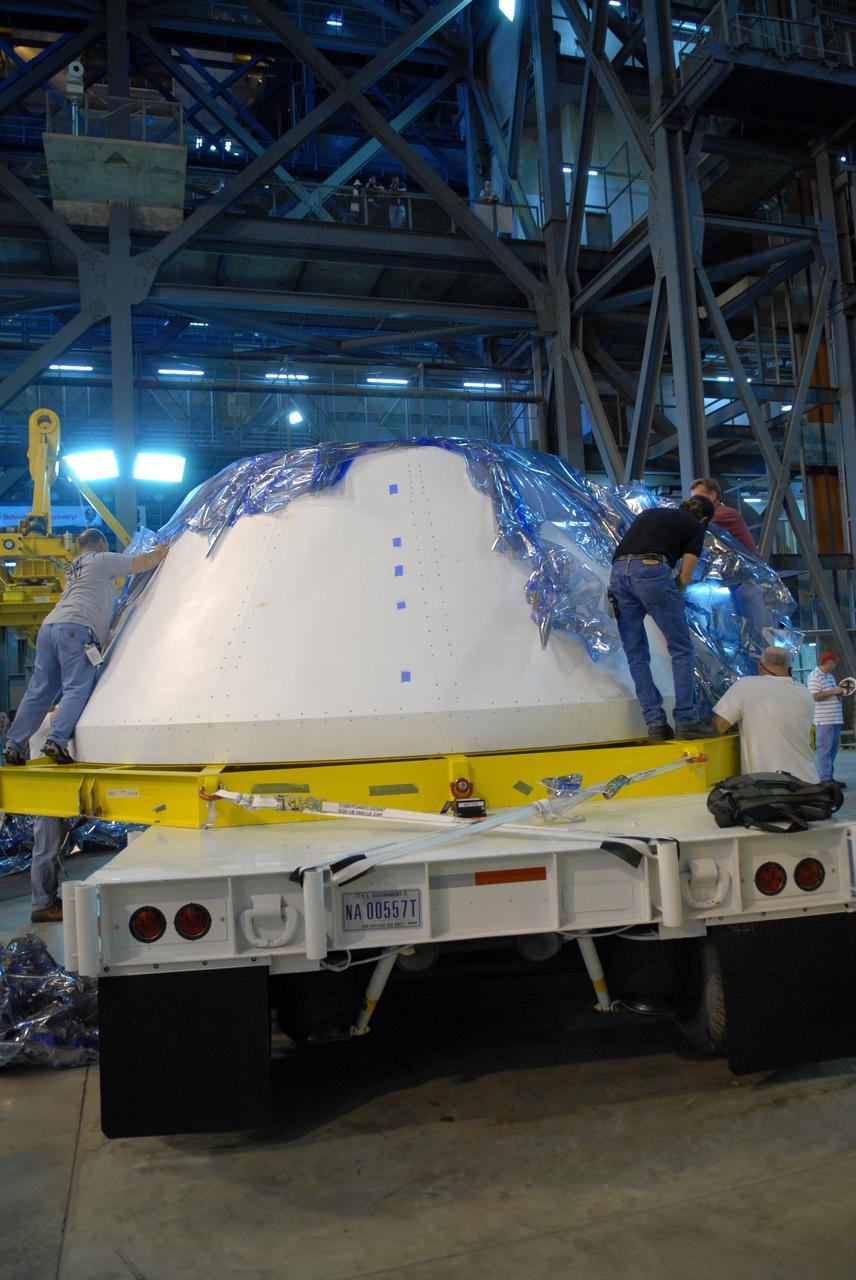 CAPE CANAVERAL, Fla. – In the Vehicle Assembly Building's high bay 4 at NASA's Kennedy Space Center in Florida, workers remove the protective blue cover from the simulator crew module for the Ares I-X rocket. The precisely machined, full-scale simulator crew module is part of the hardware that will be used in the launch of the rocket. Also arriving is a launch abort system that, with the module, will form the tip of the rocket. Ares I-X is the test flight for the Ares I. The I-X flight will provide NASA an early opportunity to test and prove hardware, facilities and ground operations associated with Ares I. The launch of the 321-foot-tall, full-scale Ares I-X, targeted for July 2009, will be the first in a series of unpiloted rocket launches from Kennedy. When fully developed, the 16-foot diameter crew module will furnish living space and reentry protection for the astronauts, while their launch abort system will provide safe evacuation if a launch vehicle failure occurs. Photo credit: NASA/Jack Pfaller