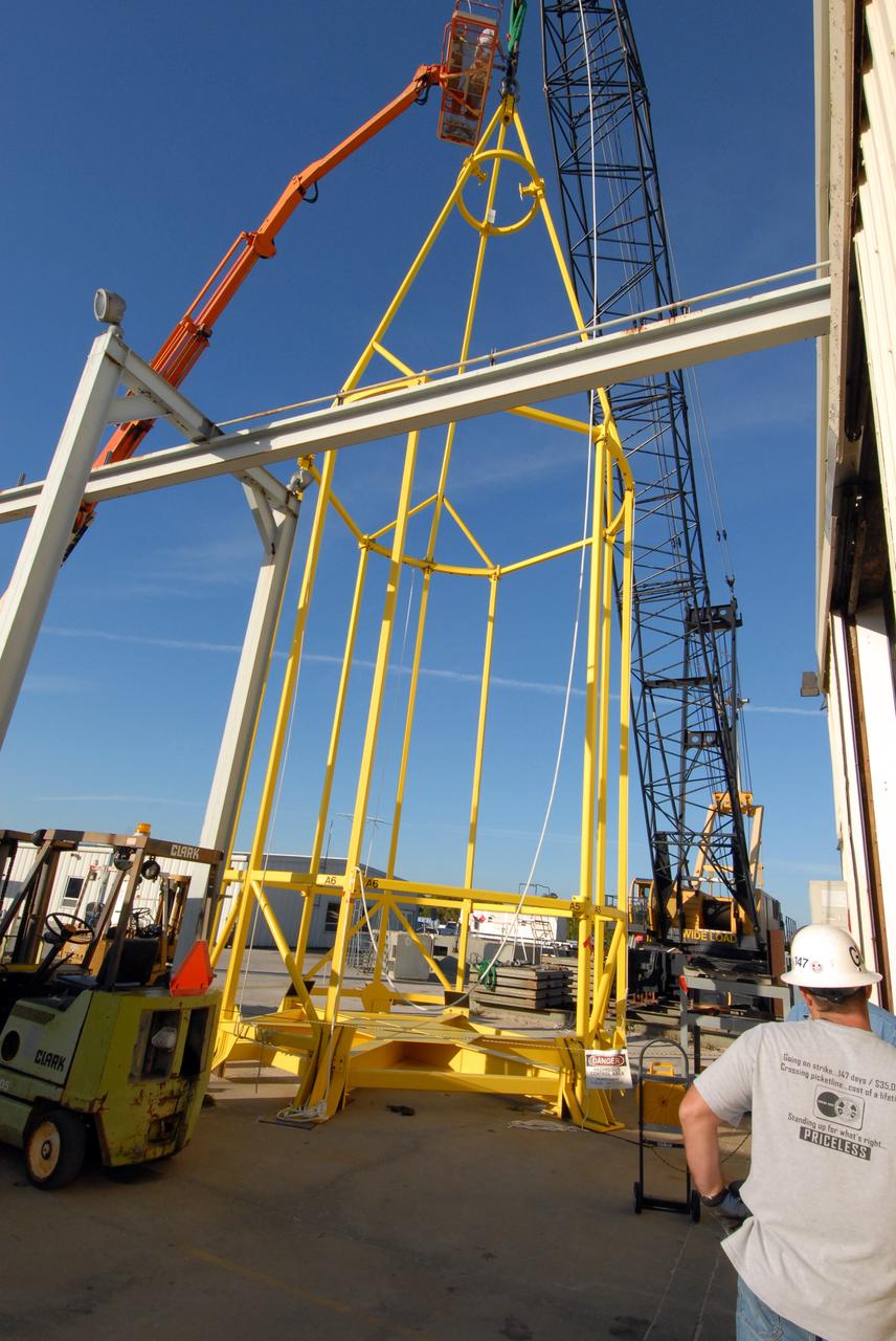 CAPE CANAVERAL, Fla. –    The yellow framework seen here is the lifting fixture nicknamed the "Birdcage" that will have the ability to lift the Crew Module, or CM, and Launch Abort System, or LAS, assembly for the Ares I-X rocket and to stack and de-stack the assembly from the Service Module/Spacecraft Adapter assembly.  It will also have the ability to lift and to stack and de-stack Stack-5  (all of the above components) from the Ares I-X in the Vehicle Assembly Building at NASA's Kennedy Space Center in Florida. Ares I-X is the test flight for the Ares I.   The I-X flight will provide NASA an early opportunity to test and prove hardware, facilities and ground operations associated with Ares I. The launch of the 321-foot-tall, full-scale Ares I-X, targeted for July 2009, will be the first in a series of unpiloted rocket launches from Kennedy. When fully developed, the 16-foot diameter crew module will furnish living space and reentry protection for the astronauts, while their launch abort system will provide safe evacuation if a launch vehicle failure occurs.   Photo credit: NASA/Jack Pfaller