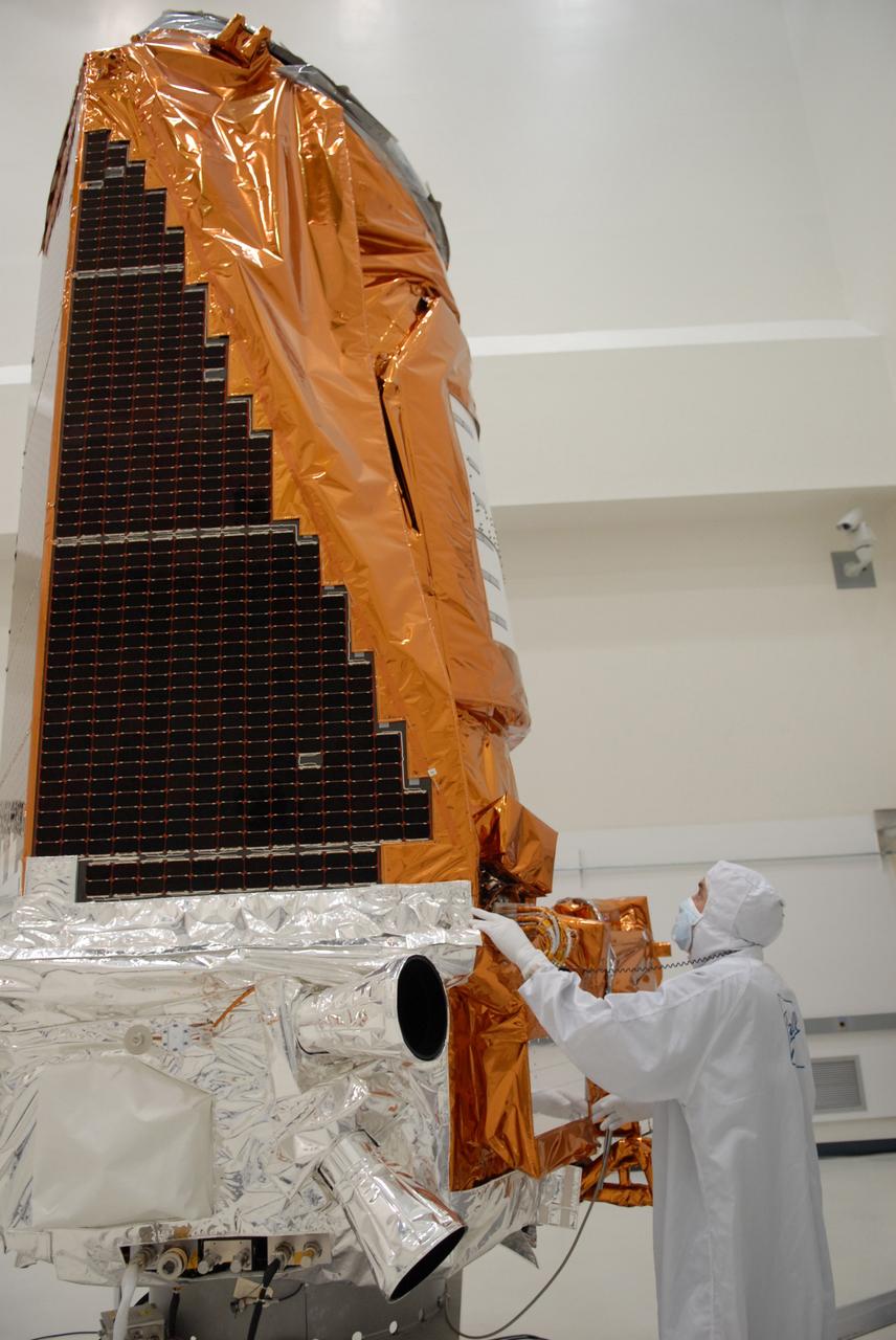 CAPE CANAVERAL, Fla. – During a media event at the Astrotech Space Operations facility in Titusville, Fla., a Ball Aerospace technician looks over NASA's Kepler spacecraft. Visible on top are the solar arrays. The event provided media representatives an opportunity to photograph the space telescope and to interview project officials from NASA and Ball Aerospace, builder of the spacecraft. Kepler is designed to survey more that 100,000 stars in our galaxy to determine the number of sun-like stars that have Earth-size and larger planets, including those that lie in a star's "habitable zone," a region where liquid water, and perhaps life, could exist. If these Earth-size worlds do exist around stars like our sun, Kepler is expected to be the first to find them and the first to measure how common they are. The liftoff of Kepler aboard a Delta II rocket is currently planned for 10:48 p.m. EST March 5 from Space Launch Complex 17 on Cape Canaveral Air Force Station. Photo credit: NASA/Troy Cryder