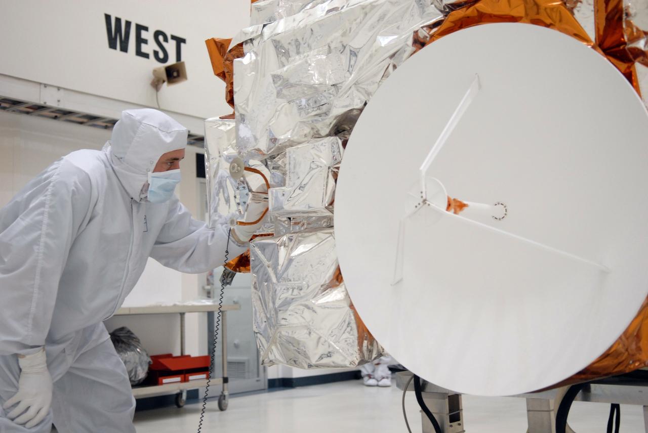 CAPE CANAVERAL, Fla. – During a media event at the Astrotech Space Operations facility in Titusville, Fla., a Ball Aerospace technician looks over NASA's Kepler spacecraft. At right is the high-gain antenna. The event provided media representatives an opportunity to photograph the space telescope and to interview project officials from NASA and Ball Aerospace, builder of the spacecraft. Kepler is designed to survey more that 100,000 stars in our galaxy to determine the number of sun-like stars that have Earth-size and larger planets, including those that lie in a star's "habitable zone," a region where liquid water, and perhaps life, could exist. If these Earth-size worlds do exist around stars like our sun, Kepler is expected to be the first to find them and the first to measure how common they are. The liftoff of Kepler aboard a Delta II rocket is currently planned for 10:48 p.m. EST March 5 from Space Launch Complex 17 on Cape Canaveral Air Force Station. Photo credit: NASA/Troy Cryder