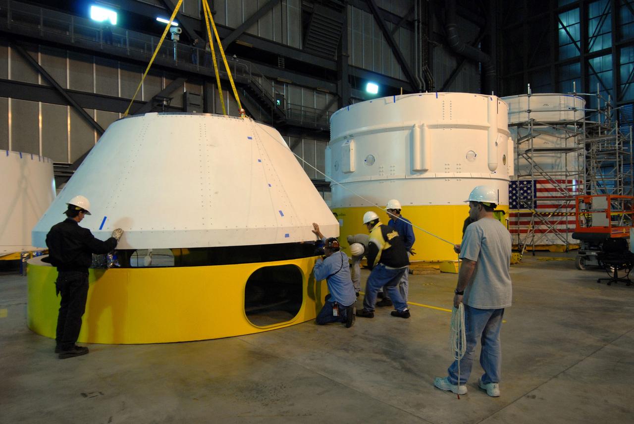 CAPE CANAVERAL, Fla. –   In high bay 4 of the Vehicle Assembly Building at NASA's Kennedy Space Center in Florida, the newly arrived simulator crew module for the Ares I-X rocket is lowered onto a work stand. Ares I-X is the test flight for the Ares I.  The I-X flight will provide NASA an early opportunity to test and prove hardware, facilities and ground operations associated with Ares I. The launch of the 321-foot-tall, full-scale Ares I-X, targeted for July 2009, will be the first in a series of unpiloted rocket launches from Kennedy. When fully developed, the 16-foot diameter crew module will furnish living space and reentry protection for the astronauts.  Photo credit: NASA/Jack Pfaller
