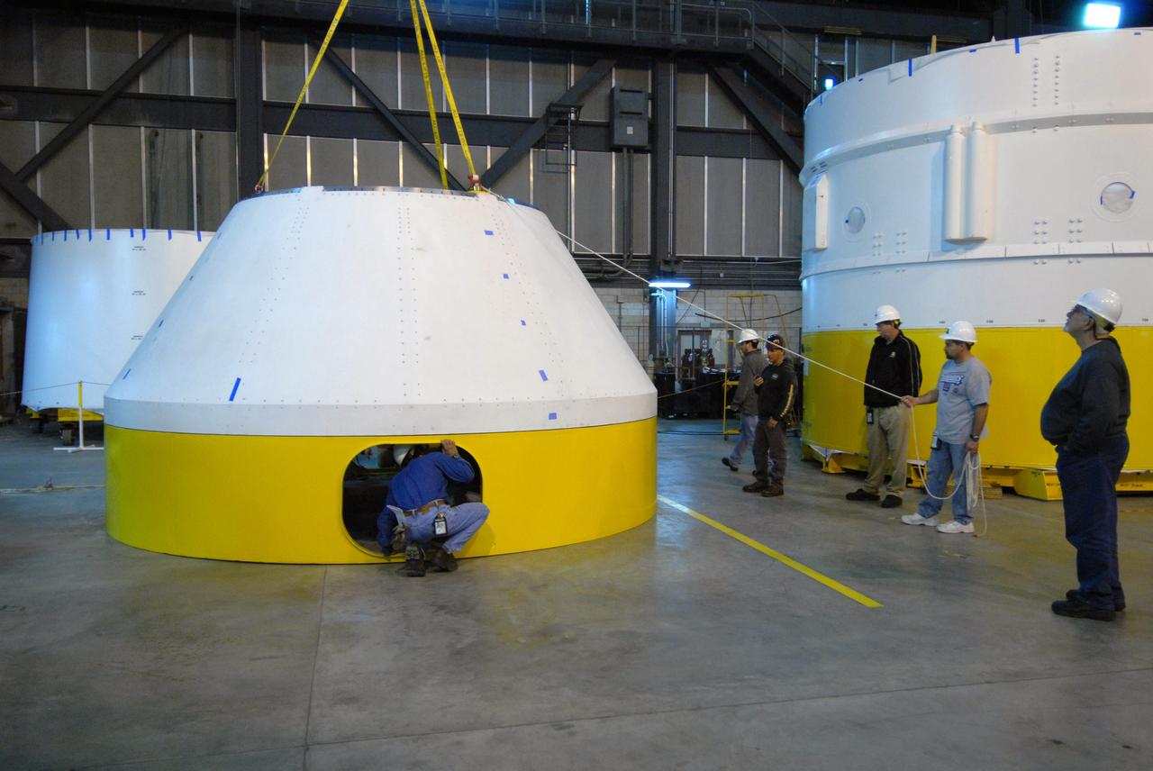 CAPE CANAVERAL, Fla. –   In high bay 4 of the Vehicle Assembly Building at NASA's Kennedy Space Center in Florida, the newly arrived simulator crew module for the Ares I-X rocket is lowered onto a work stand.  Ares I-X is the test flight for the Ares I.  The I-X flight will provide NASA an early opportunity to test and prove hardware, facilities and ground operations associated with Ares I. The launch of the 321-foot-tall, full-scale Ares I-X, targeted for July 2009, will be the first in a series of unpiloted rocket launches from Kennedy. When fully developed, the 16-foot diameter crew module will furnish living space and reentry protection for the astronauts.  Photo credit: NASA/Jack Pfaller