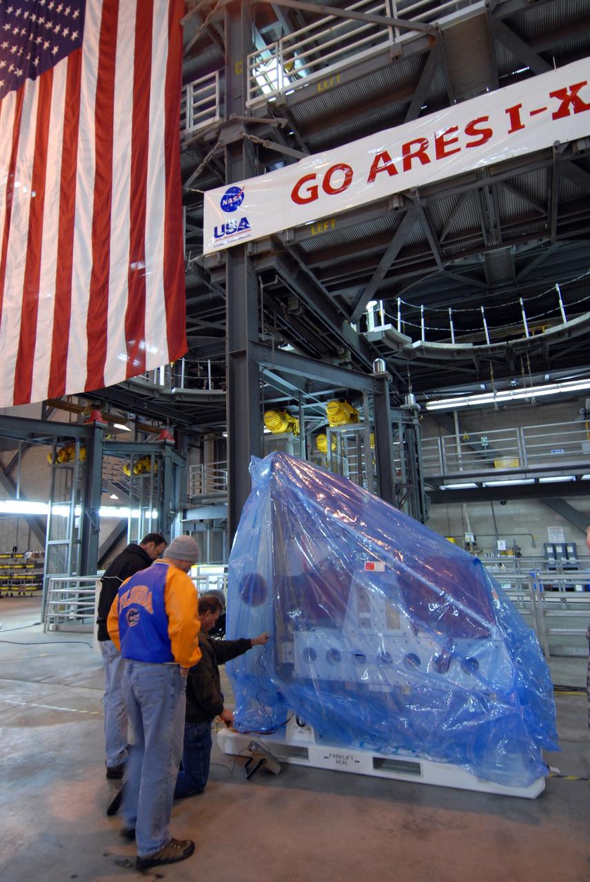 CAPE CANAVERAL, Fla. – In the Vehicle Assembly Building at NASA's Kennedy Space Center in Florida, workers look at the Ares I-X roll control system module before removing the plastic wrap. The system is designed to perform a 90-degree roll after the rocket clears the launch tower, preventing a roll during flight and maintaining the orientation of the rocket until separation of the upper and first stages. Part of the upper stage simulator, the system module is composed to two modules and four thrusters. The system module will return to earth and splash down; it will not be recovered. Ares I-X is the test vehicle for the Ares I, which is part of the Constellation Program to return men to the moon and beyond. Ares I is the essential core of a safe, reliable, cost-effective space transportation system that eventually will carry crewed missions back to the moon, on to Mars and out into the solar system. Ares I-X is targeted for launch in July 2009. Photo credit: NASA/Jack Pfaller