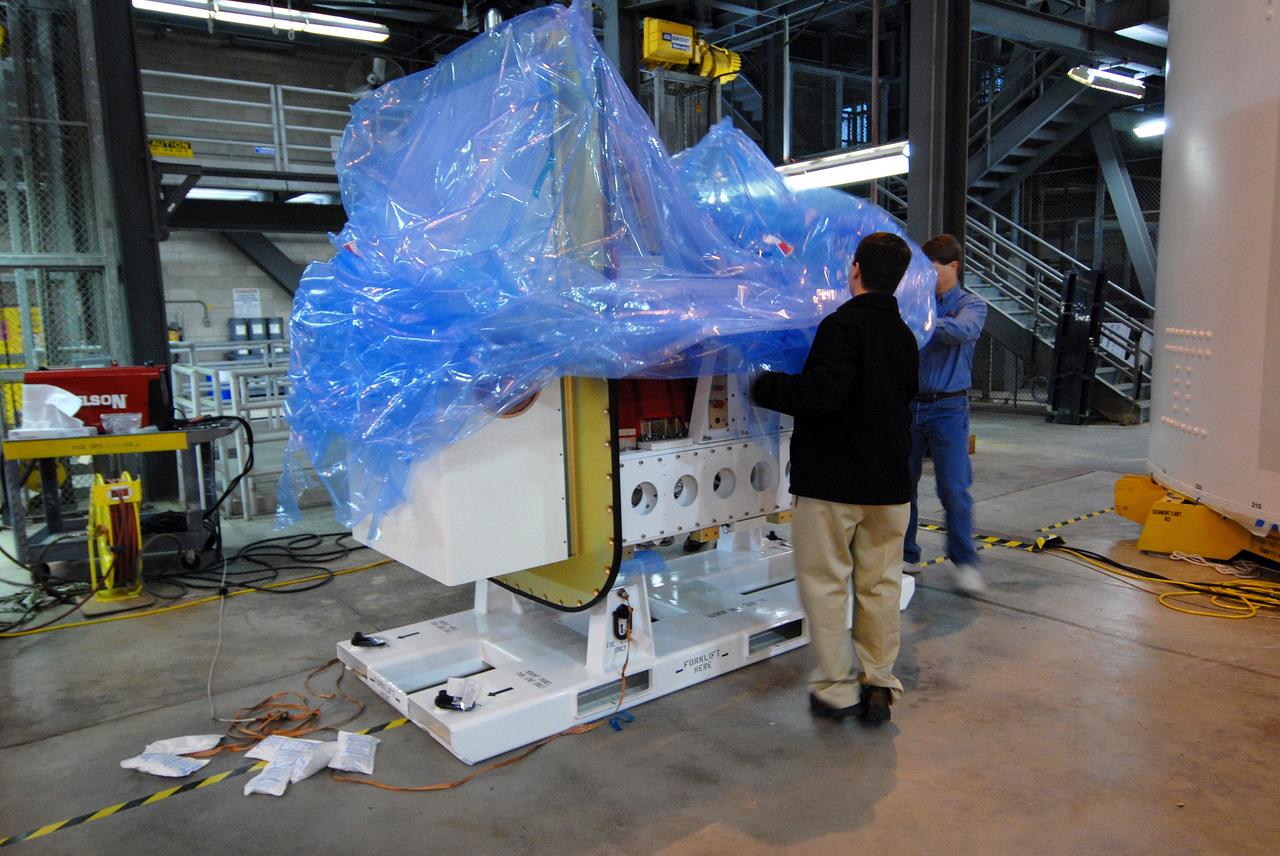 CAPE CANAVERAL, Fla. – On the floor of the Vehicle Assembly Building at NASA's Kennedy Space Center in Florida, workers start removing the plastic wrap from the Ares I-X roll control system module. The system is designed to perform a 90-degree roll after the rocket clears the launch tower, preventing a roll during flight and maintaining the orientation of the rocket until separation of the upper and first stages. Part of the upper stage simulator, the system module is composed to two modules and four thrusters. The system module will return to earth and splash down; it will not be recovered. Ares I-X is the test vehicle for the Ares I, which is part of the Constellation Program to return men to the moon and beyond. Ares I is the essential core of a safe, reliable, cost-effective space transportation system that eventually will carry crewed missions back to the moon, on to Mars and out into the solar system. Ares I-X is targeted for launch in July 2009. Photo credit: NASA/Jack Pfaller