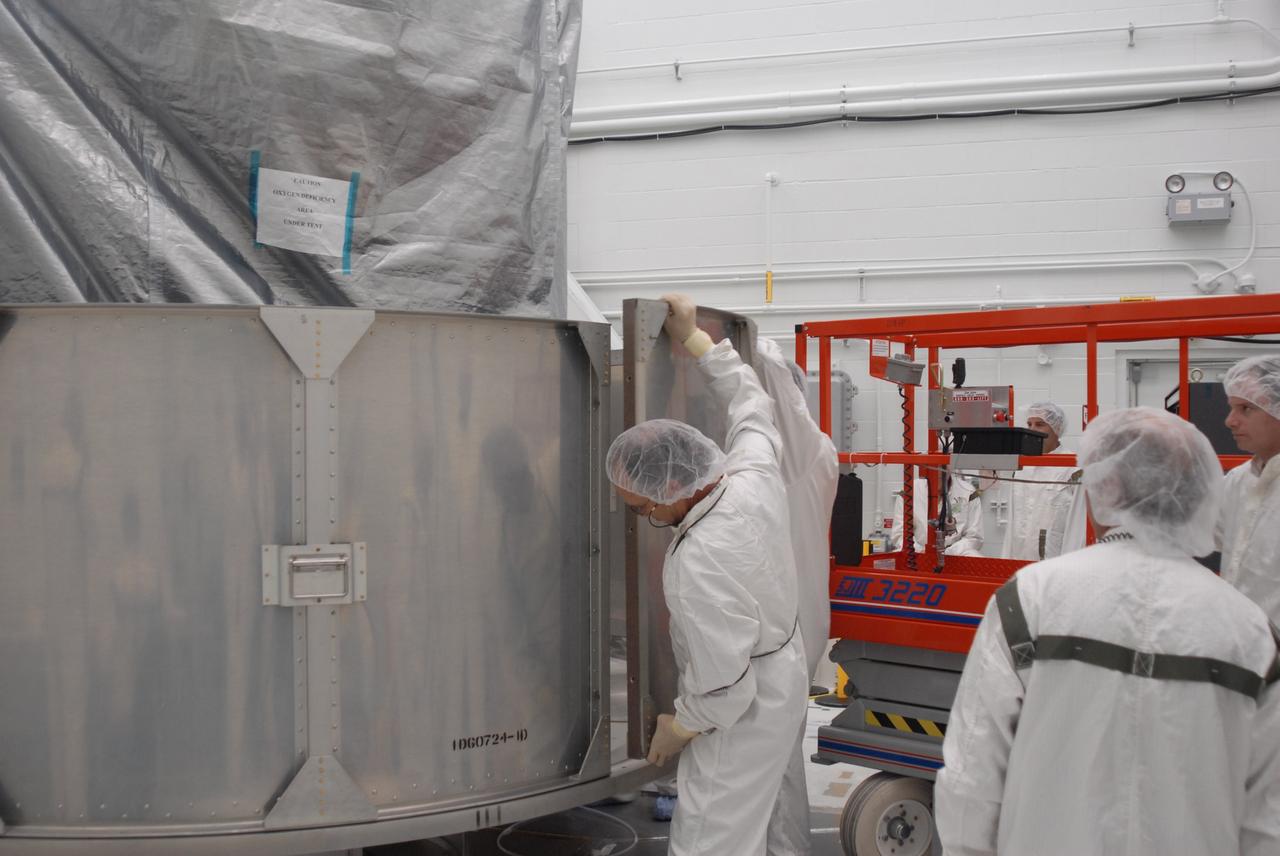 VANDENBERG AIR FORCE BASE, Calif. --  In Bldg. 1610 at Vandenberg Air Force Base in California, workers place another lower segment of a transportation canister around the NOAA-N Prime spacecraft.  NOAA-N Prime is the latest polar-orbiting operational environmental weather satellite developed by NASA for the National Oceanic and Atmospheric Administration.  The satellite is scheduled to launch Feb. 4 aboard a Delta II rocket from Vandenberg Air Force Base. Photo credit: NASA/ Daniel Liberotti, VAFB