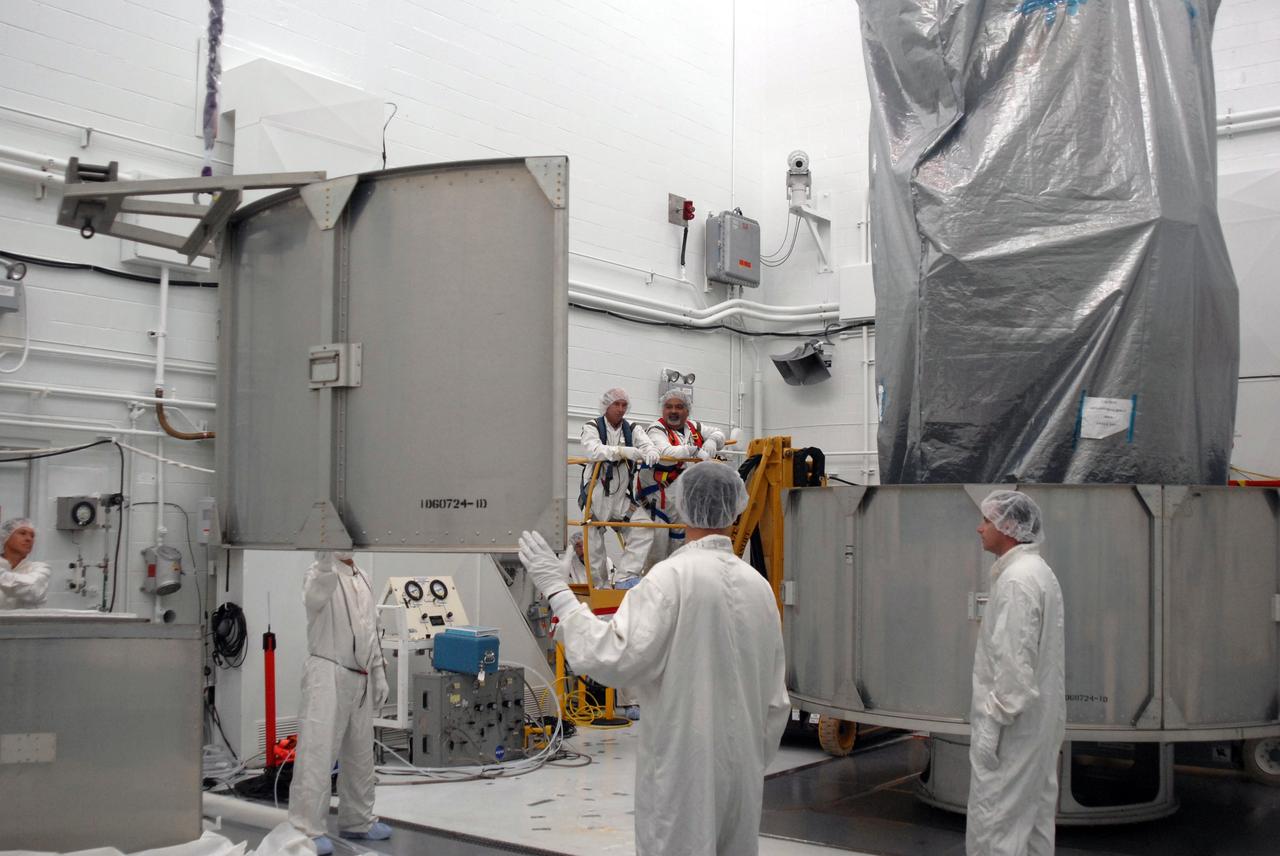 VANDENBERG AIR FORCE BASE, Calif. --  In Bldg. 1610 at Vandenberg Air Force Base in California, workers help guide a second-row segment of a transportation canister toward the NOAA-N Prime spacecraft for installation. NOAA-N Prime is the latest polar-orbiting operational environmental weather satellite developed by NASA for the National Oceanic and Atmospheric Administration.  The satellite is scheduled to launch Feb. 4 aboard a Delta II rocket from Vandenberg Air Force Base. Photo credit: NASA/ Daniel Liberotti, VAFB