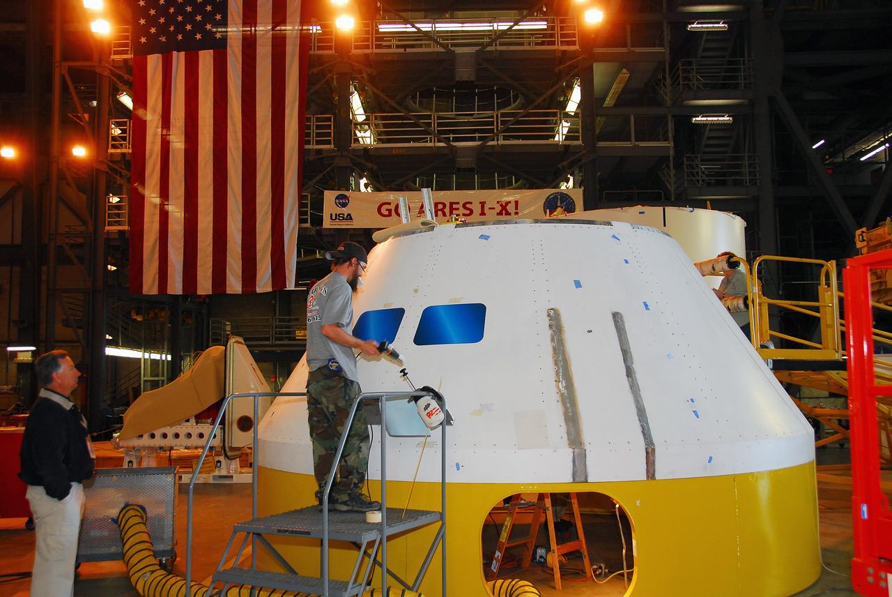 CAPE CANAVERAL, Fla. –   In high bay 4 of the Vehicle Assembly Building at NASA's Kennedy Space Center, a worker applies a window decal on the Ares I-X mock-up crew module.   Ares I-X is the test flight for the Ares I.   The I-X flight will provide NASA an early opportunity to test and prove hardware, facilities and ground operations associated with Ares I. The launch of full-scale Ares I-X, targeted for July 2009, will be the first in a series of unpiloted rocket launches from Kennedy. When fully developed, the 16-foot diameter crew module will furnish living space and reentry protection for the astronauts.  Photo credit: NASA/Tim Jacobs