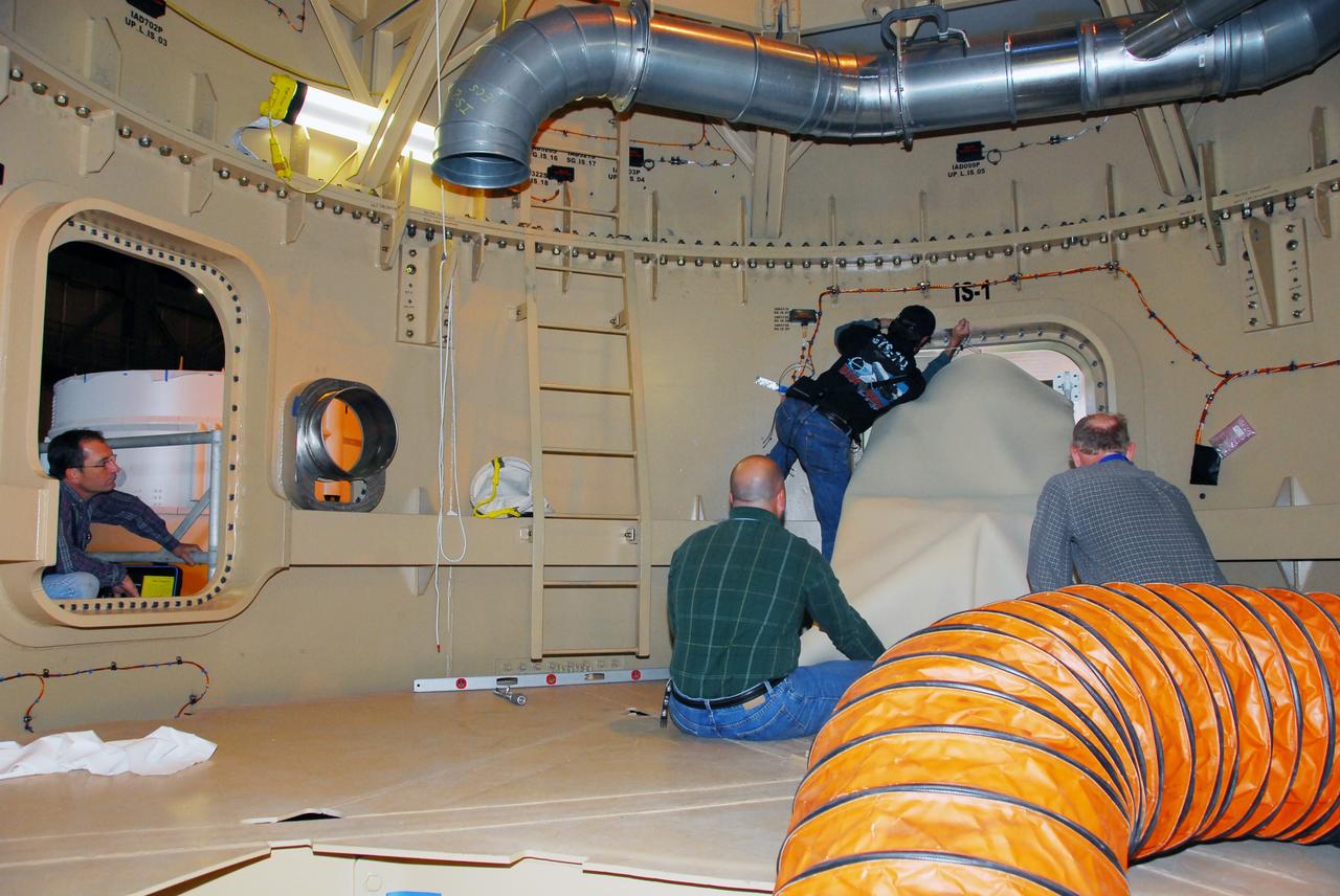 CAPE CANAVERAL, Fla. – Inside the Ares I-X upper stage simulator, workers check the fit of the roll control system module. The hardware is in high bay 4 of the Vehicle Assembly Building at NASA's Kennedy Space Center. The system is designed to perform a 90-degree roll after the rocket clears the launch tower, preventing a roll during flight and maintaining the orientation of the rocket until separation of the upper and first stages. The system module will return to earth and splash down; it will not be recovered. Ares I-X is the test vehicle for the Ares I, which is part of the Constellation Program to return men to the moon and beyond. Ares I-X is targeted for launch in summer of 2009. Photo credit: NASA/Tim Jacobs