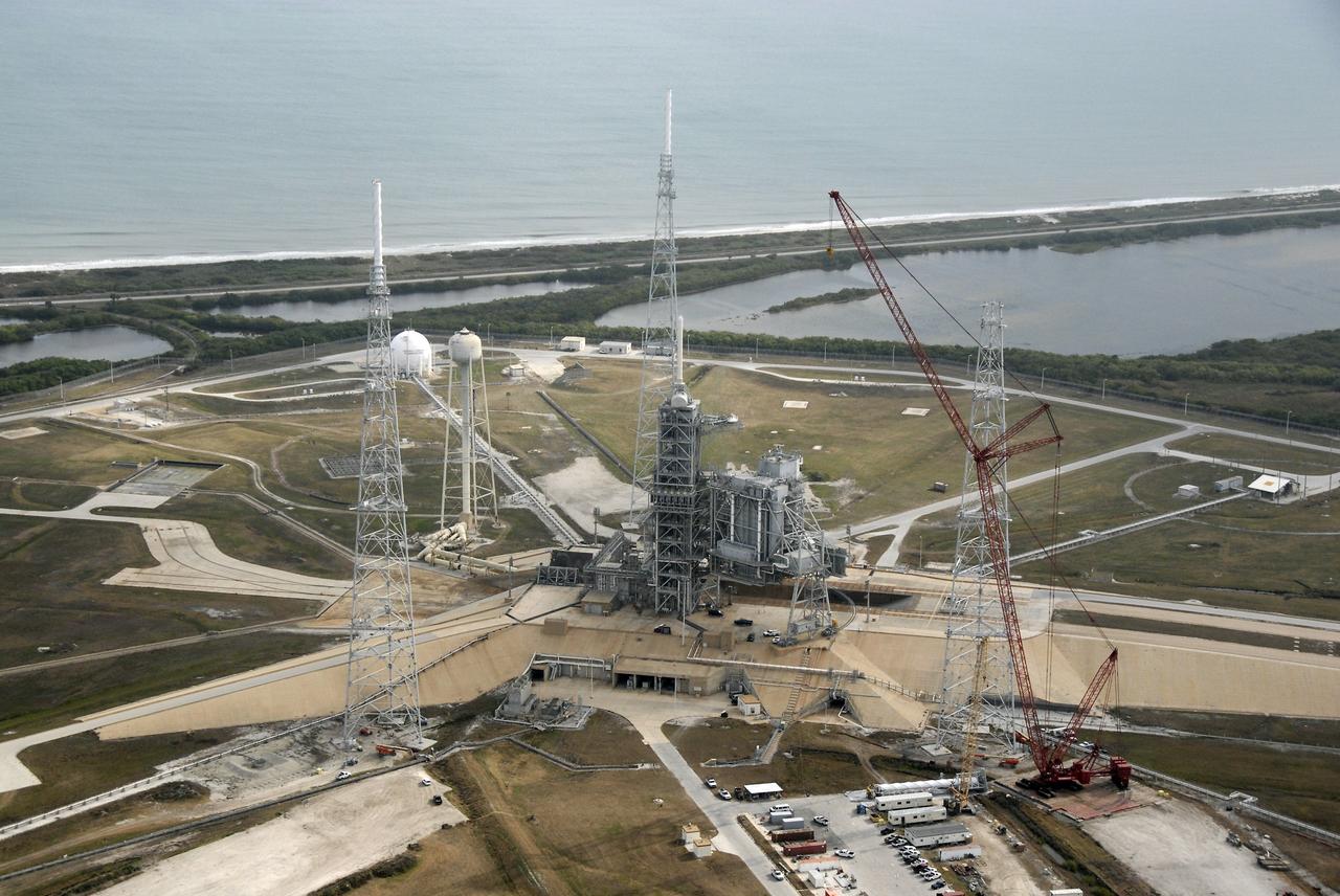 CAPE CANAVERAL, Fla. – An aerial view of the newly erected lightning towers on Launch Pad 39B at NASA's Kennedy Space Center in Florida.  The two towers at left and center contain the lightning mast on top; the one at right does not.  At center are the fixed and rotating service structures that have served the Space Shuttle Program.  Beyond the pad is the Atlantic Ocean. The new lightning protection system is being built for the Constellation Program and Ares/Orion launches.  Each of the towers is 500 feet tall with an additional 100-foot fiberglass mast atop supporting a wire catenary system.  This improved lightning protection system allows for the taller height of the Ares I rocket compared to the space shuttle.  Pad 39B will be the site of the first Ares vehicle launch, including the Ares I-X test flight that is targeted for July 2009. Photo credit: NASA/Kim Shiflett