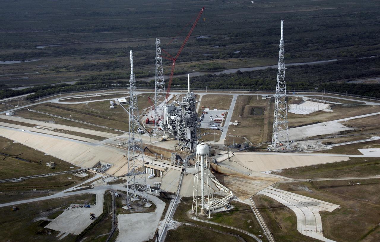 CAPE CANAVERAL, Fla. – An aerial view of the newly erected lightning towers on Launch Pad 39B at NASA's Kennedy Space Center in Florida. The two towers at left and right contain the lightning mast on top; the one at center does not. At center are the fixed and rotating service structures that have served the Space Shuttle Program. In the foreground is the tower that holds 300,000 gallons of water used for sound suppression during a shuttle liftoff. The new lightning protection system is being built for the Constellation Program and Ares/Orion launches. Each of the towers is 500 feet tall with an additional 100-foot fiberglass mast atop supporting a wire catenary system. This improved lightning protection system allows for the taller height of the Ares I rocket compared to the space shuttle. Pad 39B will be the site of the first Ares rocket launch, including the Ares I-X test flight that is targeted for July 2009. Photo credit: NASA/Kim Shiflett