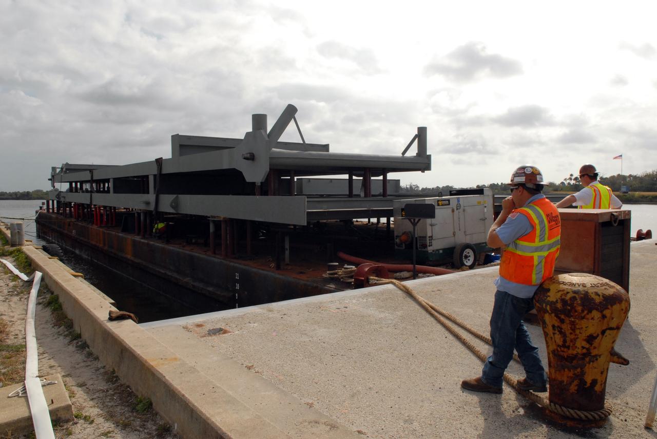 CAPE CANAVERAL, Fla. – At the turn basin in the Launch Complex 39 Area of NASA's Kennedy Space Center in Florida, the barge carrying a girder for a new mobile launcher is moved closer to the ramp. The new mobile launcher will be the base for the Ares rockets to launch the Orion crew exploration vehicle and the cargo vehicle.  The base is being made lighter than space shuttle mobile launcher platforms so the crawler-transporter can pick up the added load of the 345-foot tower and taller rocket.  When the structural portion of the new mobile launcher is complete, umbilicals, access arms, communications equipment and command/control equipment will be installed. Photo credit: NASA/Jack Pfaller