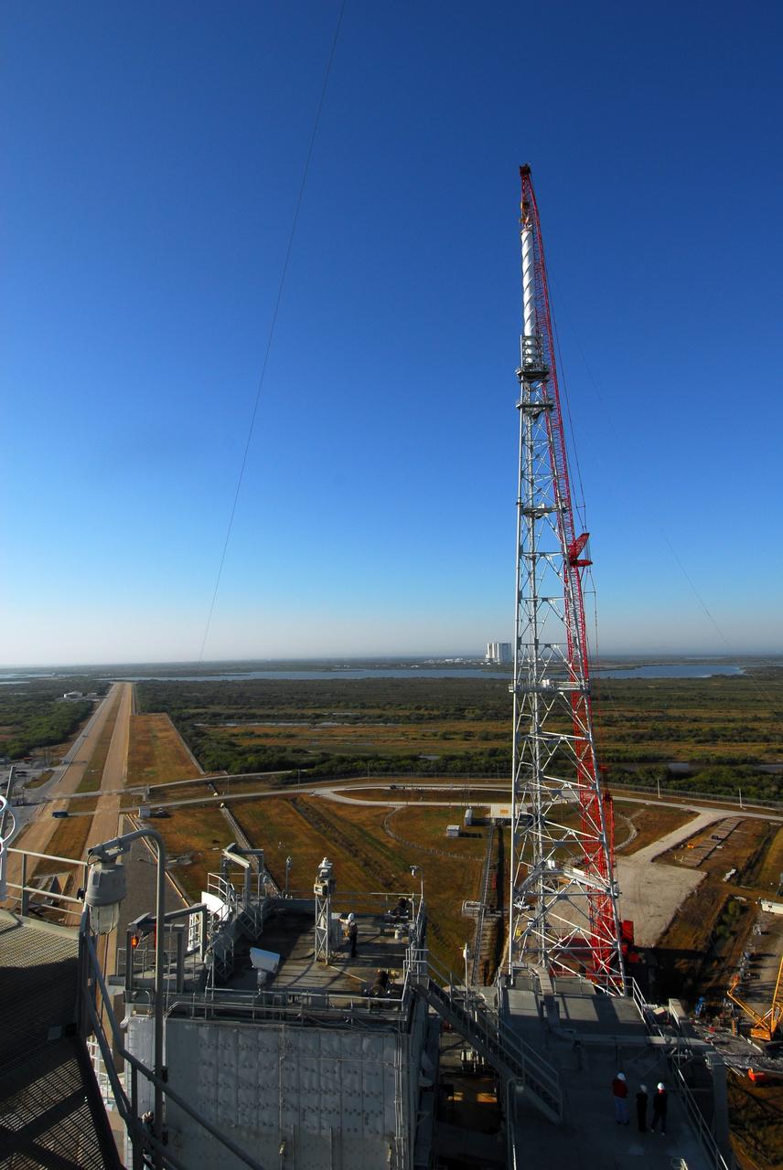 CAPE CANAVERAL, Fla. – On Launch Pad 39B at NASA's Kennedy Space Center in Florida, a giant crane places the 100-foot lightning mast on top of the newly erected lightning tower, one of three around the pad.   The new lightning protection system is being built for the Constellation Program and Ares/Orion launches.  Each of the towers is 500 feet tall with an additional 100-foot fiberglass mast atop supporting a wire catenary system.  This improved lightning protection system allows for the taller height of the Ares I rocket compared to the space shuttle.  Pad 39B will be the site of the first Ares vehicle launch, including the Ares I-X test flight that is targeted for July 2009. Photo credit: NASA/Tim Jacobs