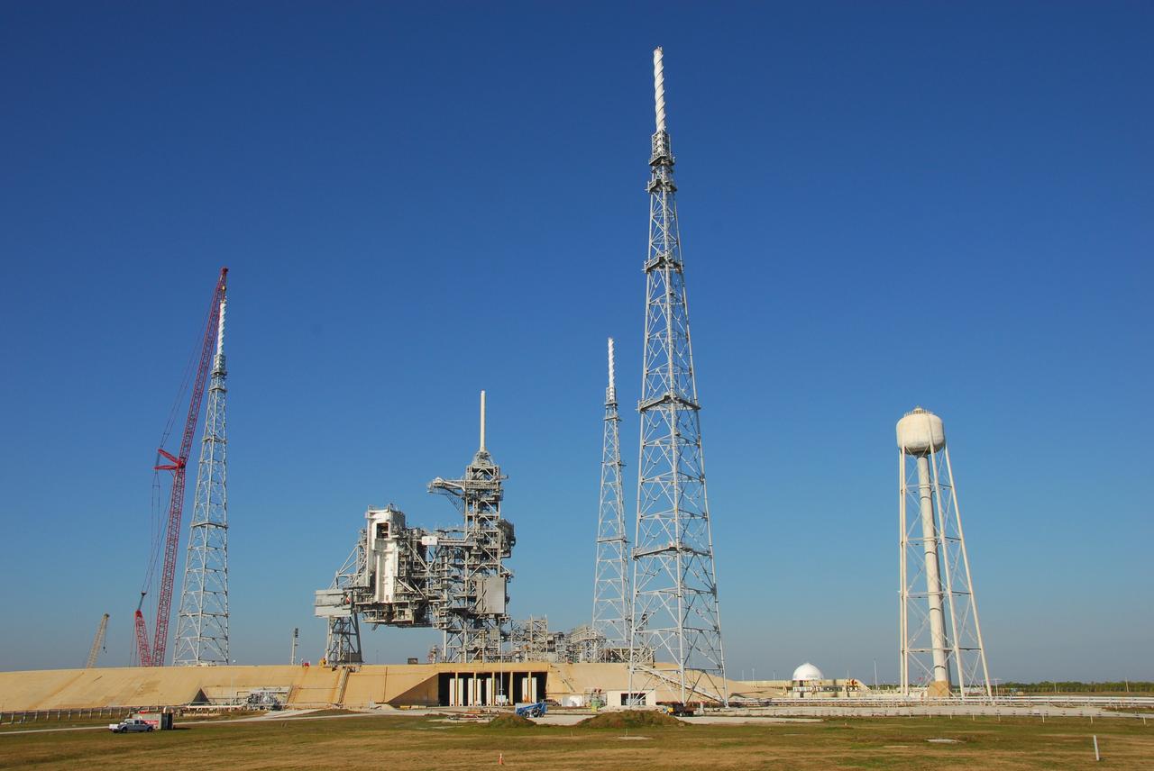 CAPE CANAVERAL, Fla. – On Launch Pad 39B at NASA's Kennedy Space Center in Florida, a giant crane (far left) places the 100-foot lightning mast on top of the newly erected lightning tower.  Three new towers surround the pad.  In the middle are the fixed and rotating service structures that serve the Space Shuttle Program.  At far right is the tower that holds 300,000 gallons of water used for sound suppression during a shuttle launch.  The new lightning protection system is being built for the Constellation Program and Ares/Orion launches.  Each of the towers is 500 feet tall with an additional 100-foot fiberglass mast atop supporting a wire catenary system.  This improved lightning protection system allows for the taller height of the Ares I rocket compared to the space shuttle.  Pad 39B will be the site of the first Ares vehicle launch, including the Ares I-X test flight that is targeted for July 2009. Photo credit: NASA/Tim Jacobs