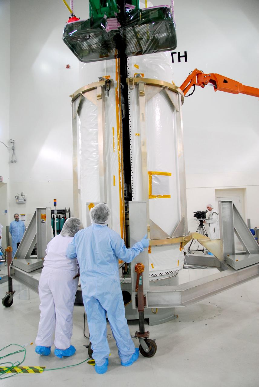 VANDENBERG AIR FORCE BASE, Calif. --  Workers check the movement of the fairing at right toward NASA's Orbiting Carbon Observatory, or OCO, at left, to complete installation.  The work is being done in Building 1032 of Vandenberg Air Force Base in California. The fairing is a molded structure that fits flush with the outside surface of the rocket and forms an aerodynamically smooth nose cone, protecting the spacecraft during launch and ascent. The spacecraft is scheduled for launch aboard Orbital Sciences' Taurus XL rocket on Feb. 23 from Vandenberg. The spacecraft will collect precise global measurements of carbon dioxide (CO2) in the Earth's atmosphere. Scientists will analyze OCO data to improve our understanding of the natural processes and human activities that regulate the abundance and distribution of this important greenhouse gas. This improved understanding will enable more reliable forecasts of future changes in the abundance and distribution of CO2 in the atmosphere and the effect that these changes may have on the Earth's climate. Photo credit: NASA/Robert Hargreaves Jr., VAFB