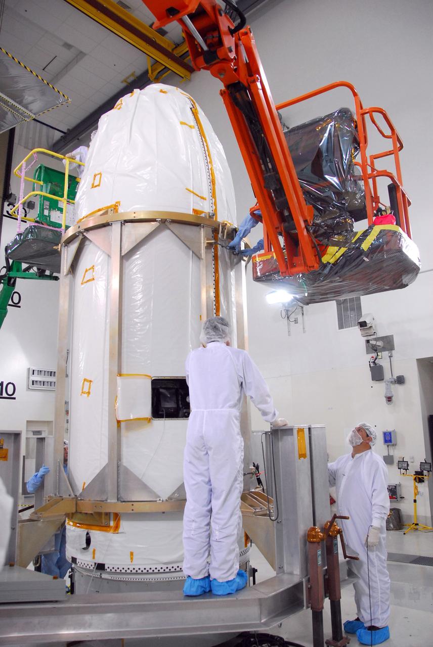 VANDENBERG AIR FORCE BASE, Calif. --  Workers secure the installation of the fairing around NASA's Orbiting Carbon Observatory, or OCO.  The work is being done in Building 1032 of Vandenberg Air Force Base in California. The fairing is a molded structure that fits flush with the outside surface of the rocket and forms an aerodynamically smooth nose cone, protecting the spacecraft during launch and ascent. The spacecraft is scheduled for launch aboard Orbital Sciences' Taurus XL rocket on Feb. 23 from Vandenberg. The spacecraft will collect precise global measurements of carbon dioxide (CO2) in the Earth's atmosphere. Scientists will analyze OCO data to improve our understanding of the natural processes and human activities that regulate the abundance and distribution of this important greenhouse gas. This improved understanding will enable more reliable forecasts of future changes in the abundance and distribution of CO2 in the atmosphere and the effect that these changes may have on the Earth's climate. Photo credit: NASA/Robert Hargreaves Jr., VAFB