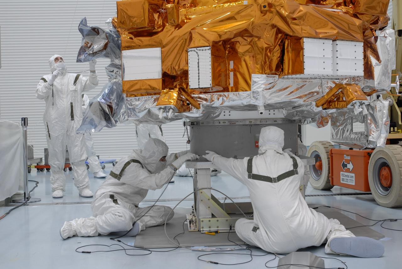 CAPE CANAVERAL, Fla. – At the Hazardous Processing Facility at Astrotech in Titusville, Fla., workers attach cables from the overhead crane onto the Kepler spacecraft. The crane will lift and weigh the spacecraft. Kepler is designed to survey more than 100,000 stars in our galaxy to determine the number of sun-like stars that have Earth-size and larger planets, including those that lie in a star's "habitable zone," a region where liquid water, and perhaps life, could exist. If these Earth-size worlds do exist around stars like our sun, Kepler is expected to be the first to find them and the first to measure how common they are. The liftoff of Kepler aboard a Delta II rocket is currently targeted for 10:48 p.m. EST March 5 from Space Launch Complex 17 on Cape Canaveral Air Force Station. Photo credit: NASA/Jim Grossmann