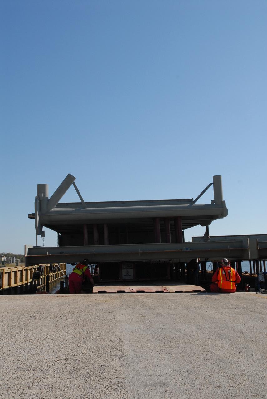 CAPE CANAVERAL, Fla. – At the turn basin at NASA's Kennedy Space Center in Florida, the girder for the new mobile launcher rests on a long transporter that will move it off the barge.   The new mobile launcher will be the base for the Ares rockets to launch the Orion crew exploration vehicle and the cargo vehicle.  The base is being made lighter than space shuttle mobile launcher platforms so the crawler-transporter can pick up the added load of the 345-foot tower and taller rocket.  When the structural portion of the new mobile launcher is complete, umbilicals, access arms, communications equipment and command/control equipment will be installed.  Photo credit: NASA/Jack Pfaller