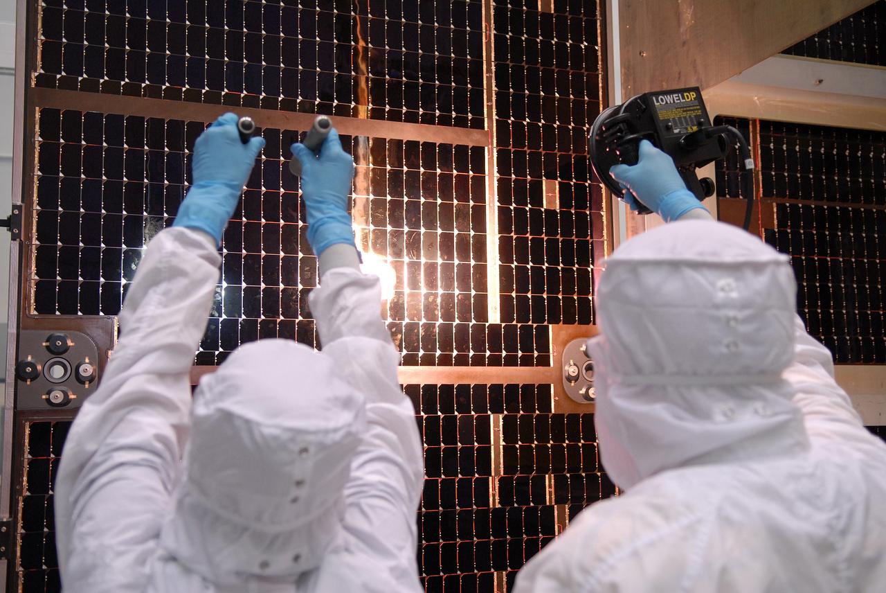 CAPE CANAVERAL, Fla. – Technicians check out the solar arrays for NASA's Lunar Reconnaissance Orbiter, or LRO, at the Astrotech processing facility in Titusville, Fla.  The spacecraft was built by engineers at Goddard Space Flight Center, where it recently completed two months of tests in a thermal vacuum chamber. The orbiter will carry seven instruments to provide scientists with detailed maps of the lunar surface and enhance our understanding of the moon's topography, lighting conditions, mineralogical composition and natural resources. Information gleaned from LRO will be used to select safe landing sites, determine locations for future lunar outposts and help mitigate radiation dangers to astronauts. The polar regions of the moon are the main focus of the mission because continuous access to sunlight may be possible and water ice may exist in permanently shadowed areas of the poles. Accompanying LRO on its journey to the moon will be the Lunar Crater Observation and Sensing Satellite, or LCROSS, a mission that will impact the lunar surface in its search for water ice. Launch of LRO/LCROSS is targeted for April 24.     Photo credit: NASA/Jack Pfaller