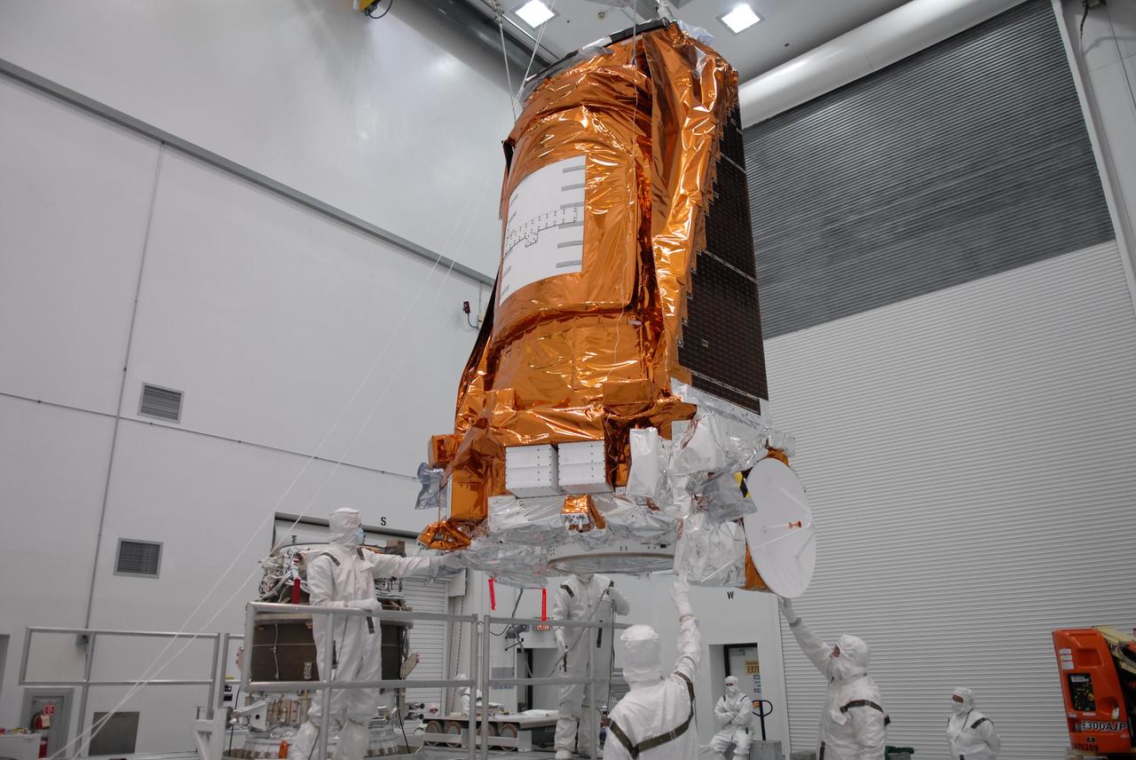 CAPE CANAVERAL, Fla. – At the Hazardous Processing Facility at Astrotech in Titusville, Fla., workers guide the suspended Kepler spacecraft toward a Delta II third stage. Kepler is designed to survey more than 100,000 stars in our galaxy to determine the number of sun-like stars that have Earth-size and larger planets, including those that lie in a star's "habitable zone," a region where liquid water, and perhaps life, could exist. If these Earth-size worlds do exist around stars like our sun, Kepler is expected to be the first to find them and the first to measure how common they are. The liftoff of Kepler aboard a Delta II rocket is currently targeted for 10:48 p.m. EST March 5 from Space Launch Complex 17 on Cape Canaveral Air Force Station. Photo credit: NASA/Troy Cryder