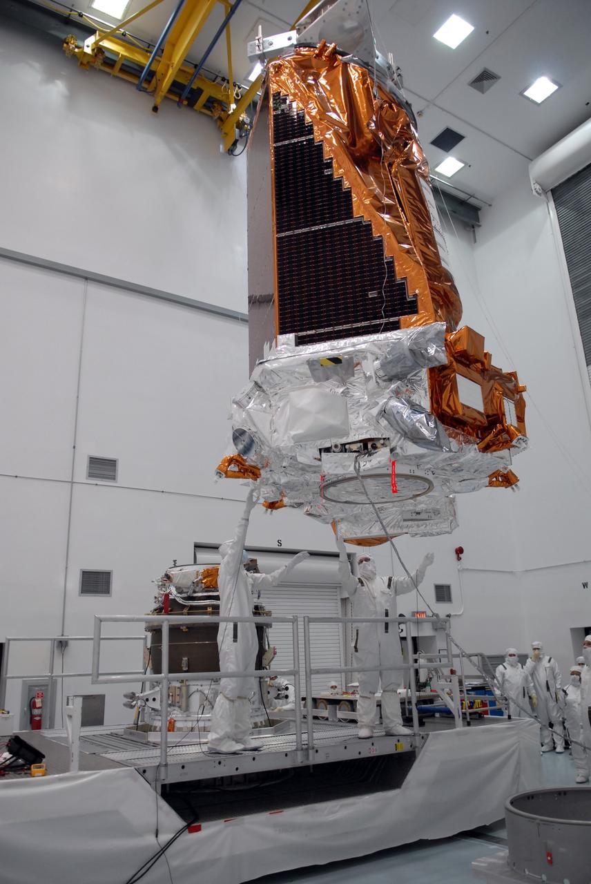 CAPE CANAVERAL, Fla. – At the Hazardous Processing Facility at Astrotech in Titusville, Fla., workers guide the suspended Kepler spacecraft toward a Delta II third stage behind them, at left. Kepler is designed to survey more than 100,000 stars in our galaxy to determine the number of sun-like stars that have Earth-size and larger planets, including those that lie in a star's "habitable zone," a region where liquid water, and perhaps life, could exist. If these Earth-size worlds do exist around stars like our sun, Kepler is expected to be the first to find them and the first to measure how common they are. The liftoff of Kepler aboard a Delta II rocket is currently targeted for 10:48 p.m. EST March 5 from Space Launch Complex 17 on Cape Canaveral Air Force Station. Photo credit: NASA/Troy Cryder