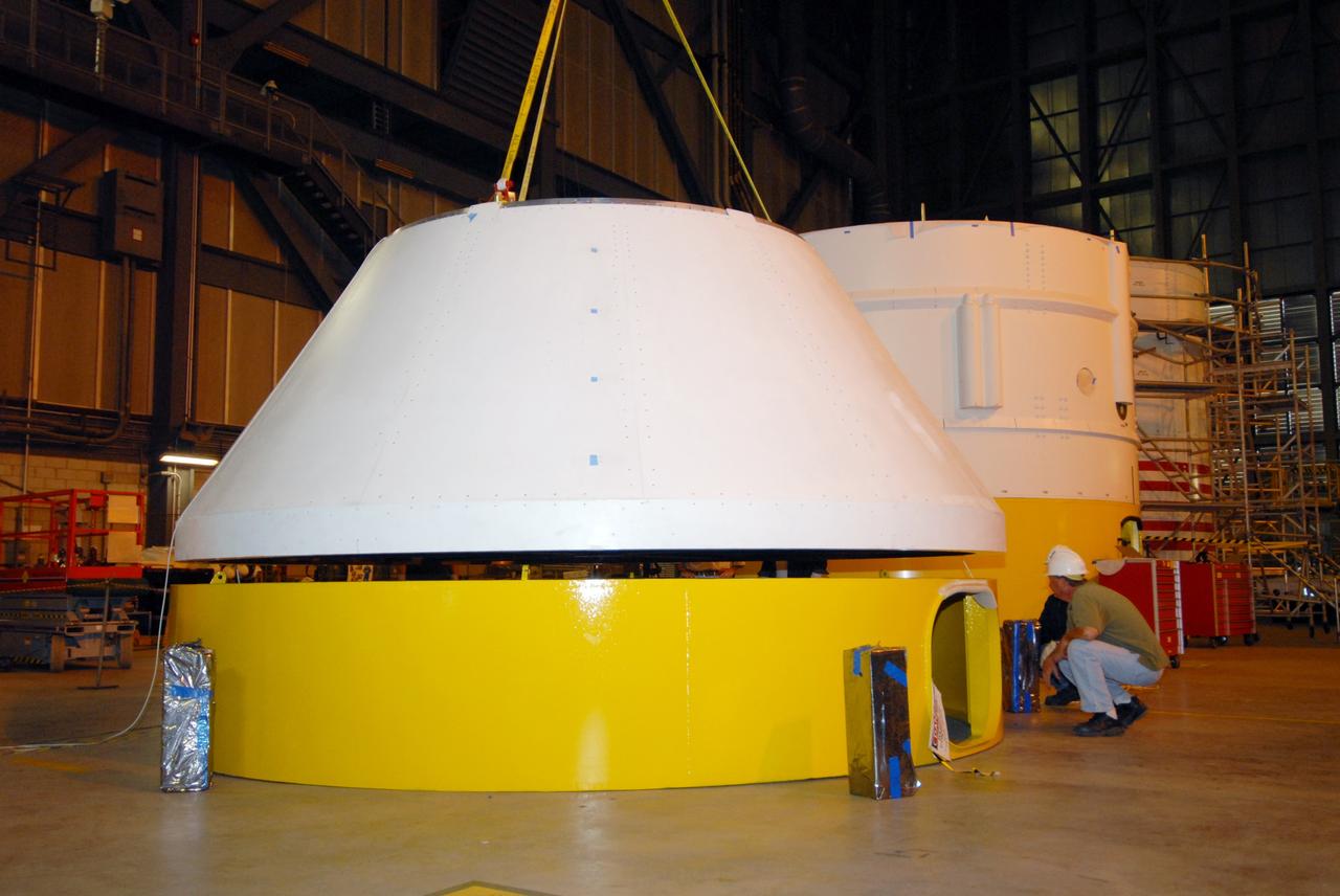 CAPE CANAVERAL, Fla. – In high bay 4 of the Vehicle Assembly Building at NASA's Kennedy Space Center, workers lift the Ares I-X crew module mock-up from a work stand for a fit check with a mock-up of the service module. When fully developed, the 16-foot diameter crew module will furnish living space and reentry protection for future astronauts, and the service module’s main engine will be used to break out of lunar orbit for the return trip to Earth. Ares I-X is the test flight for the Ares I, which is part of the Constellation Program to return men to the moon and beyond. The I-X flight will provide NASA an early opportunity to test and prove hardware, facilities and ground operations associated with Ares I launches. Targeted for the summer of 2009, the launch of the full-scale Ares I-X will be the first in a series of unpiloted rocket launches from Kennedy. Photo credit: NASA/Jack Pfaller