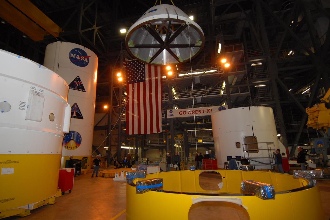 CAPE CANAVERAL, Fla. – In high bay 4 of the Vehicle Assembly Building at NASA's Kennedy Space Center, workers lift the Ares I-X crew module mock-up during a fit check with a mock-up of the service module. When fully developed, the 16-foot diameter crew module will furnish living space and reentry protection for future astronauts, and the service module’s main engine will be used to break out of lunar orbit for the return trip to Earth. Ares I-X is the test flight for the Ares I, which is part of the Constellation Program to return men to the moon and beyond. The I-X flight will provide NASA an early opportunity to test and prove hardware, facilities and ground operations associated with Ares I launches. Targeted for the summer of 2009, the launch of the full-scale Ares I-X will be the first in a series of unpiloted rocket launches from Kennedy. Photo credit: NASA/Jack Pfaller
