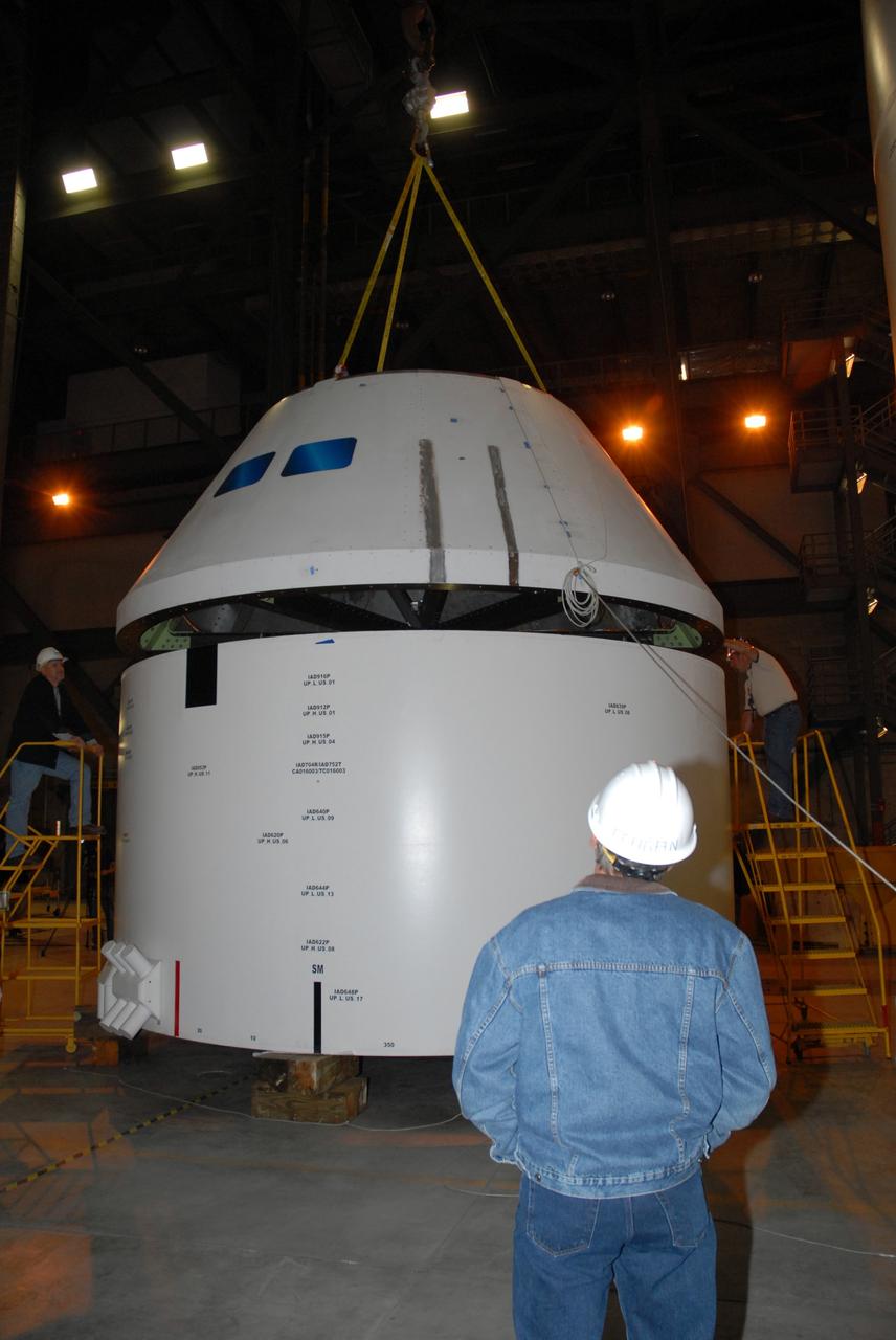 CAPE CANAVERAL, Fla. – In high bay 4 of the Vehicle Assembly Building at NASA's Kennedy Space Center, workers position the Ares I-X crew module mock-up onto a mock-up of the service module during a fit check of the hardware. When fully developed, the 16-foot diameter crew module will furnish living space and reentry protection for future astronauts, and the service module’s main engine will be used to break out of lunar orbit for the return trip to Earth. Ares I-X is the test flight for the Ares I, which is part of the Constellation Program to return men to the moon and beyond. The I-X flight will provide NASA an early opportunity to test and prove hardware, facilities and ground operations associated with Ares I launches. Targeted for the summer of 2009, the launch of the full-scale Ares I-X will be the first in a series of unpiloted rocket launches from Kennedy. Photo credit: NASA/Jack Pfaller