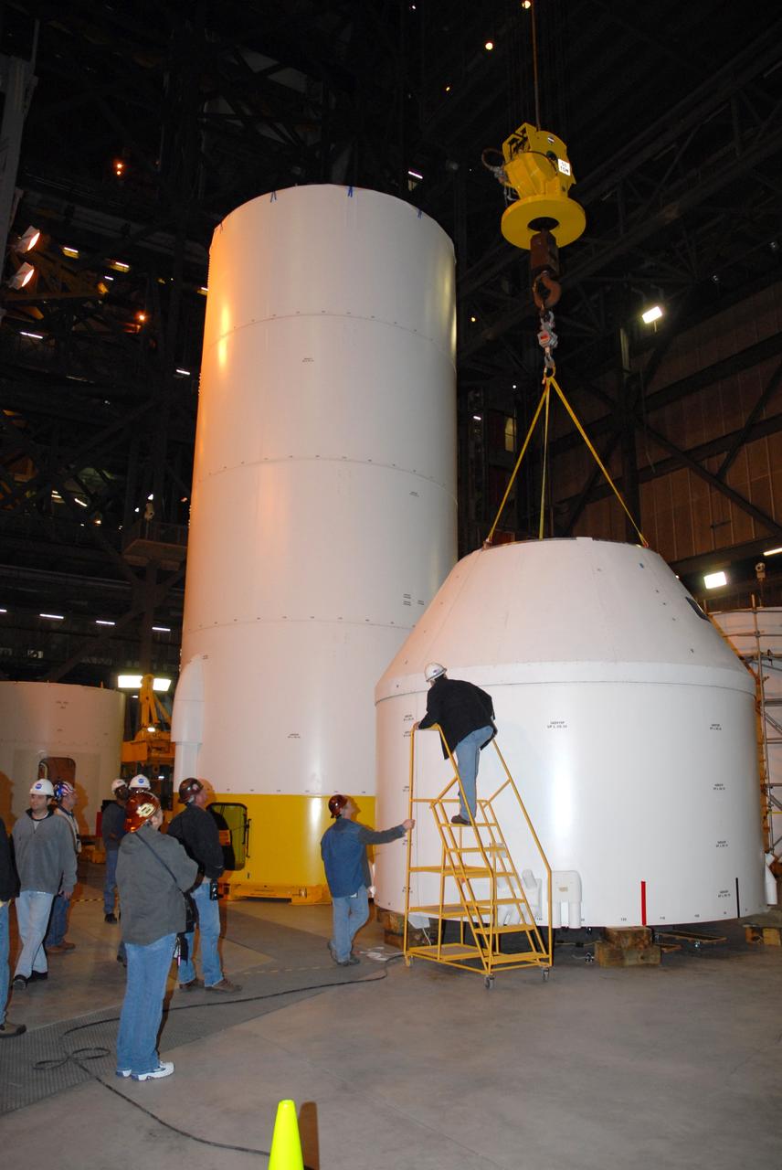 CAPE CANAVERAL, Fla. – In high bay 4 of the Vehicle Assembly Building at NASA's Kennedy Space Center, the Ares I-X crew module mock-up is positioned onto a mock-up of the service module to determine that the pieces of hardware are a perfect fit.  When fully developed, the 16-foot diameter crew module will furnish living space and reentry protection for future astronauts, and the service module’s main engine will be used to break out of lunar orbit for the return trip to Earth.  Ares I-X is the test flight for the Ares I, which is part of the Constellation Program to return men to the moon and beyond. The I-X flight will provide NASA an early opportunity to test and prove hardware, facilities and ground operations associated with Ares I launches. Targeted for the summer of 2009, the launch of the full-scale Ares I-X will be the first in a series of unpiloted rocket launches from Kennedy.   Photo credit: NASA/Jack Pfaller