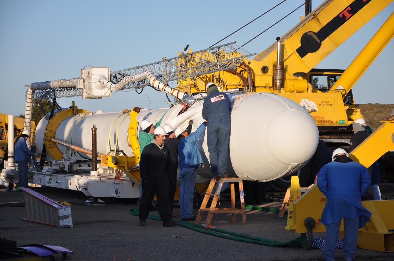 VANDENBERG AIR FORCE BASE, Calif. --  On Launch Complex 576-E at Vandenberg Air Force Base in California, workers prepare NASA's Orbiting Carbon Observatory, or OCO, upper stack for attachment to the Stage 0.  Orbital Sciences workers put the non-flight environmental shield over the fairing prior to erection.  A portion of the umbilical tower (above it) is attached to the upper stack. The umbilical tower will be erected along with the upper stack. The spacecraft is scheduled for launch aboard Orbital Sciences' Taurus XL rocket Feb. 24 from Vandenberg. The spacecraft will collect precise global measurements of carbon dioxide (CO2) in the Earth's atmosphere. Scientists will analyze OCO data to improve our understanding of the natural processes and human activities that regulate the abundance and distribution of this important greenhouse gas.   Photo credit: NASA/Randy Beaudoin, VAFB