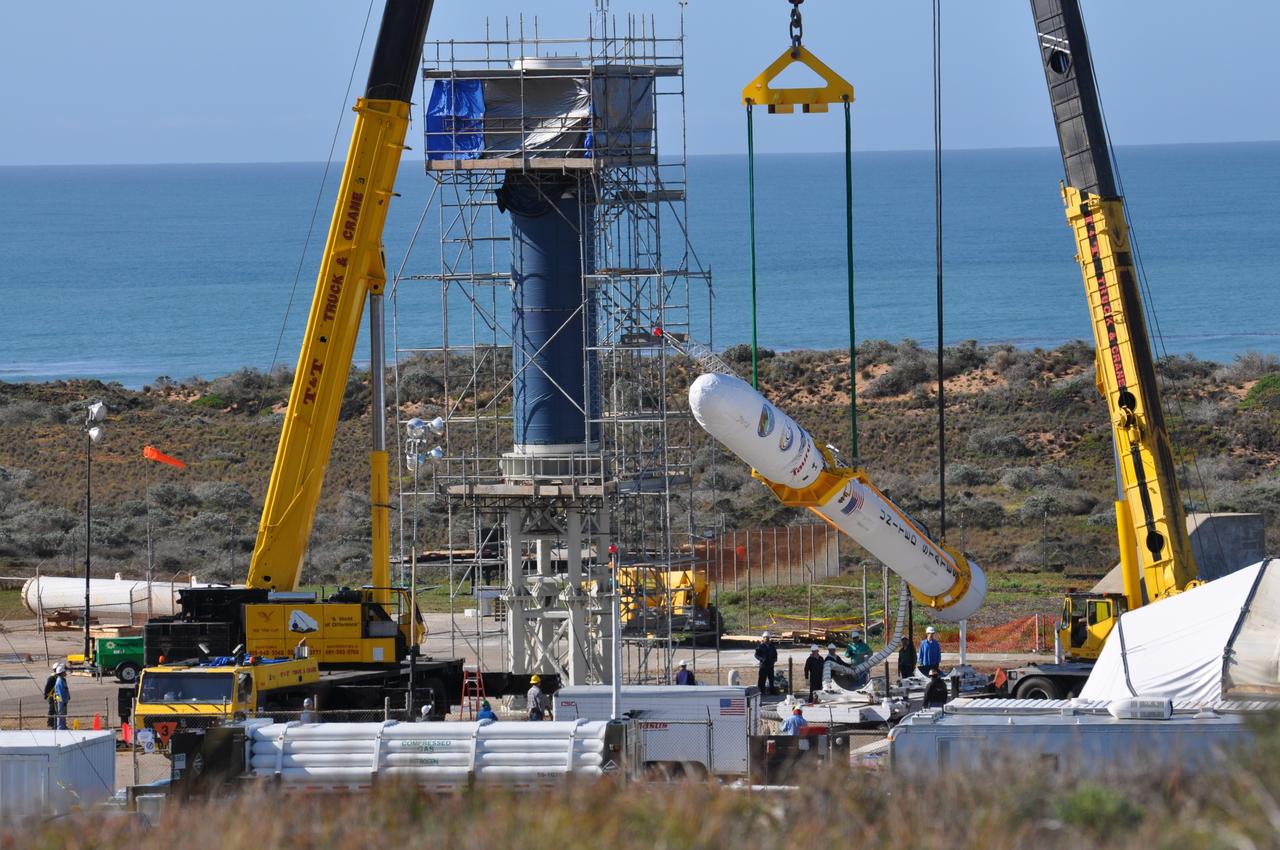 VANDENBERG AIR FORCE BASE, Calif. --  On Launch Complex 576-E at Vandenberg Air Force Base in California, two cranes raise NASA's Orbiting Carbon Observatory, or OCO, spacecraft to vertical for attachment to the waiting Stage 0 motor of the Taurus XL launch vehicle in the tower.  The OCO is attached to the upper stack, consisting of Stages 1, 2 and 3 of the Taurus. The spacecraft is scheduled for launch aboard Orbital Sciences' Taurus XL rocket Feb. 24 from Vandenberg. The spacecraft will collect precise global measurements of carbon dioxide (CO2) in the Earth's atmosphere. Scientists will analyze OCO data to improve our understanding of the natural processes and human activities that regulate the abundance and distribution of this important greenhouse gas.   Photo credit: NASA/Randy Beaudoin, VAFB