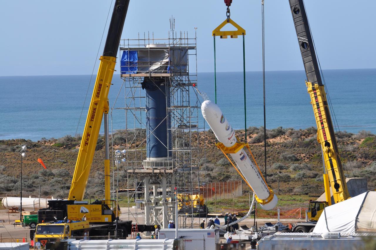 VANDENBERG AIR FORCE BASE, Calif. -- On Launch Complex 576-E at Vandenberg Air Force Base in California, two cranes raise NASA's Orbiting Carbon Observatory, or OCO, spacecraft to vertical for attachment to the waiting Stage 0 motor of the Taurus XL launch vehicle in the tower. The OCO is attached to the upper stack, consisting of Stages 1, 2 and 3 of the Taurus. The spacecraft is scheduled for launch aboard Orbital Sciences' Taurus XL rocket Feb. 24 from Vandenberg. The spacecraft will collect precise global measurements of carbon dioxide (CO2) in the Earth's atmosphere. Scientists will analyze OCO data to improve our understanding of the natural processes and human activities that regulate the abundance and distribution of this important greenhouse gas.   Photo credit: NASA/Randy Beaudoin, VAFB
