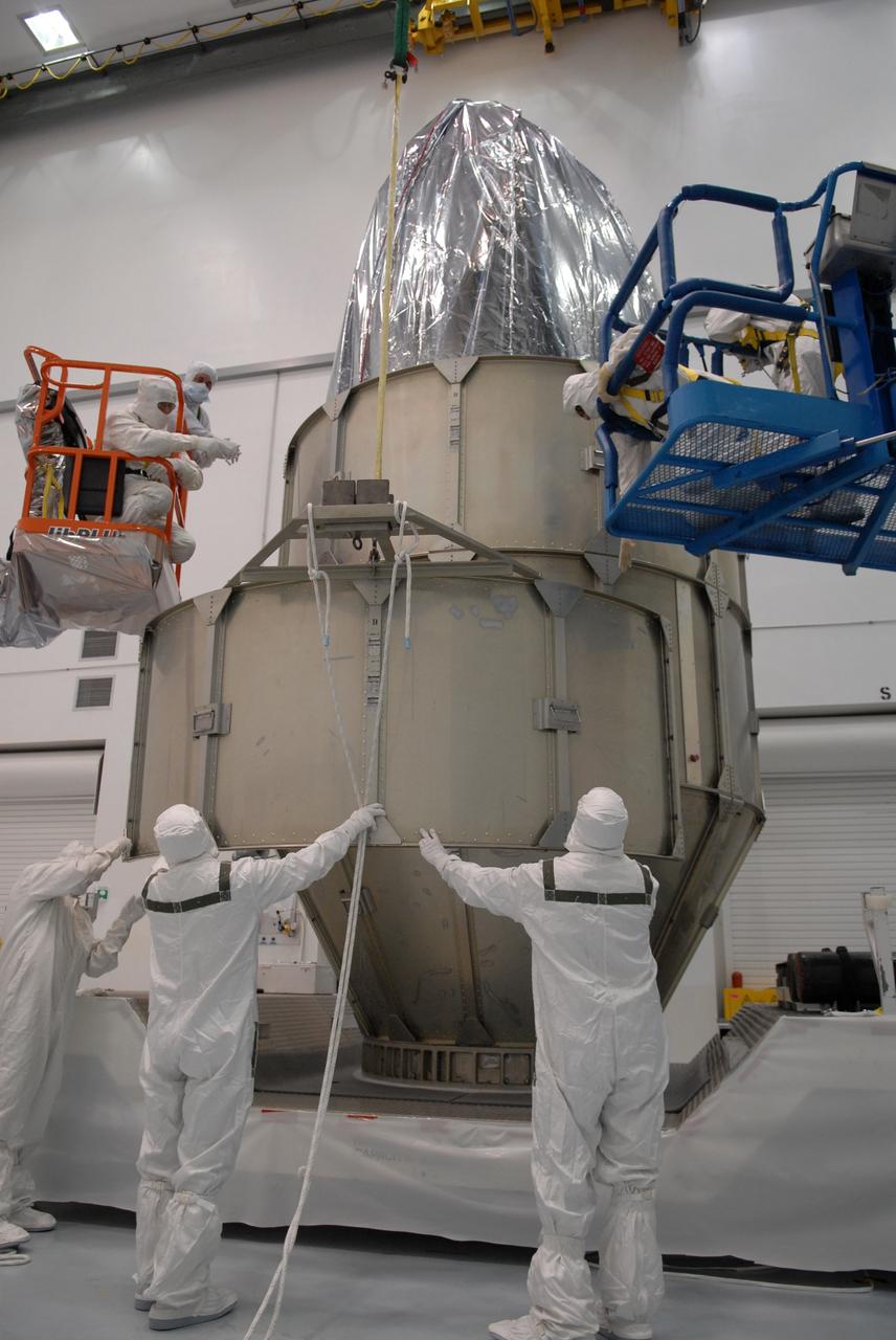 CAPE CANAVERAL, Fla. – At the Astrotech payload processing facility in Titusville, Fla., workers help guide the canister segment for NASA's Kepler spacecraft as it is lifted toward workers above. The segment will be added to the stack around Kepler. The "canning" provides protection during the spacecraft's transport to the pad. The liftoff of Kepler aboard a Delta II rocket is currently targeted for 10:48 p.m. EST March 5 from Pad 17-B. Kepler is designed to survey more than 100,000 stars in our galaxy to determine the number of sun-like stars that have Earth-size and larger planets, including those that lie in a star's "habitable zone," a region where liquid water, and perhaps life, could exist. If these Earth-size worlds do exist around stars like our sun, Kepler is expected to be the first to find them and the first to measure how common they are. Photo credit: NASA/Troy Cryder