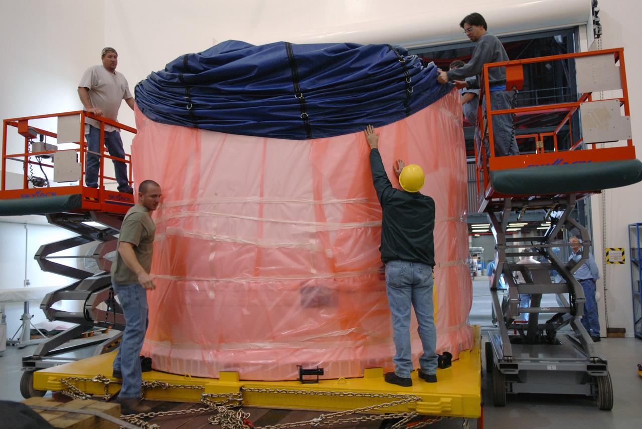 CAPE CANAVERAL, Fla. – In the extended duration orbiter lab, or EDO, of the Vehicle Assembly Building at NASA's Kennedy Space Center in Florida, workers remove the cover from the fifth segment simulator center. It will be prepared for stacking with other segments in the VAB. Ares I-X is the test vehicle for the Ares I, which is part of the Constellation Program to return men to the moon and beyond. Ares I is the essential core of a safe, reliable, cost-effective space transportation system that eventually will carry crewed missions back to the moon, on to Mars and out into the solar system. Ares I-X is targeted for launch in July 2009. Photo credit: NASA/Troy Cryder
