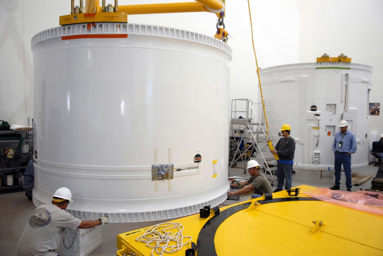 CAPE CANAVERAL, Fla. – In the extended duration orbiter lab, or EDO, of the Vehicle Assembly Building at NASA's Kennedy Space Center in Florida, workers help guide the fifth segment simulator center onto supports on the floor. Ares I-X is the test vehicle for the Ares I, which is part of the Constellation Program to return men to the moon and beyond. Ares I is the essential core of a safe, reliable, cost-effective space transportation system that eventually will carry crewed missions back to the moon, on to Mars and out into the solar system. Ares I-X is targeted for launch in July 2009. Photo credit: NASA/Troy Cryder