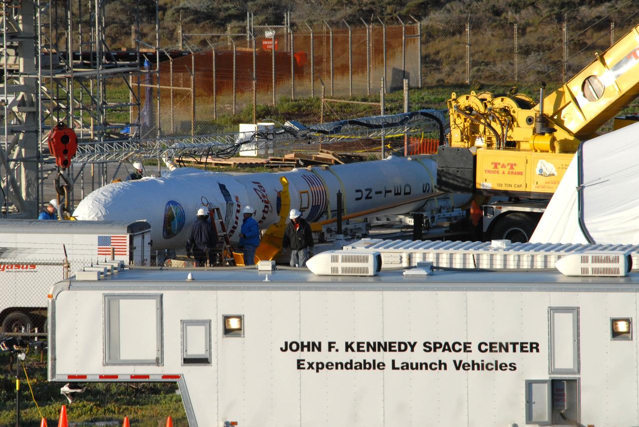 VANDENBERG AIR FORCE BASE, Calif. --  On Launch Complex 576-E at Vandenberg Air Force Base in California, workers prepare NASA's Orbiting Carbon Observatory, or OCO, upper stack for attachment to Orbital Sciences' Taurus XL rocket's Stage 0. The upper stack consists of Stages 1, 2 and 3 of the Taurus as well as the encapsulated OCO spacecraft. Orbital Sciences workers put the non-flight environmental shield over the fairing prior to erection. A portion of the umbilical tower (above it) is attached to the upper stack. OCO is scheduled for launch aboard the Taurus Feb. 24 from Vandenberg. The spacecraft will collect precise global measurements of carbon dioxide (CO2) in the Earth's atmosphere. Scientists will analyze OCO data to improve our understanding of the natural processes and human activities that regulate the abundance and distribution of this important greenhouse gas. Photo credit: NASA/Dan Liberotti, VAFB