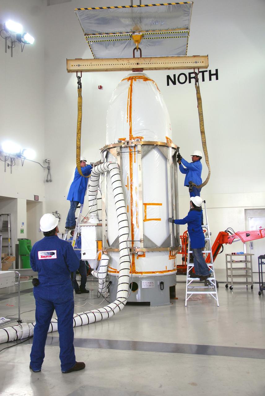 VANDENBERG AIR FORCE BASE, Calif. --  In the Astrotech payload processing facility at Vandenberg Air Force Base in California,  workers secure an overhead crane to NASA's Orbiting Carbon Observatory, or OCO.  The spacecraft will be moved to a transporter for the trip to Launch Complex 576-E.  An umbilical line (left) has been attached. OCO will collect precise global measurements of carbon dioxide (CO2) in the Earth's atmosphere. Scientists will analyze OCO data to improve our understanding of the natural processes and human activities that regulate the abundance and distribution of this important greenhouse gas. OCO is scheduled to launch Feb. 24 aboard an Orbital Sciences' Taurus XL rocket.  Photo credit: NASA/VAFB