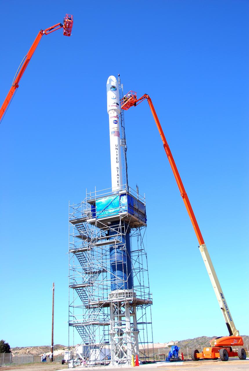 VANDENBERG AIR FORCE BASE, Calif. --  On Launch Complex 576-E at Vandenberg Air Force Base in California, Orbital Sciences Engineer Jose Castillo maneuvers the bucket truck into position over the fairing access door on NASA's Orbiting Carbon Observatory, or OCO.  On the top of the OCO fairing is the shadow of Glenn Weigle of Orbital Satellite Systems Group, on the bucket at upper left, who is prepared to move in and inspect the GN2 instrument purge flow. OCO will collect precise global measurements of carbon dioxide (CO2) in the Earth's atmosphere. Scientists will analyze OCO data to improve our understanding of the natural processes and human activities that regulate the abundance and distribution of this important greenhouse gas.  Photo credit: NASA/Richard Nielsen, KSC