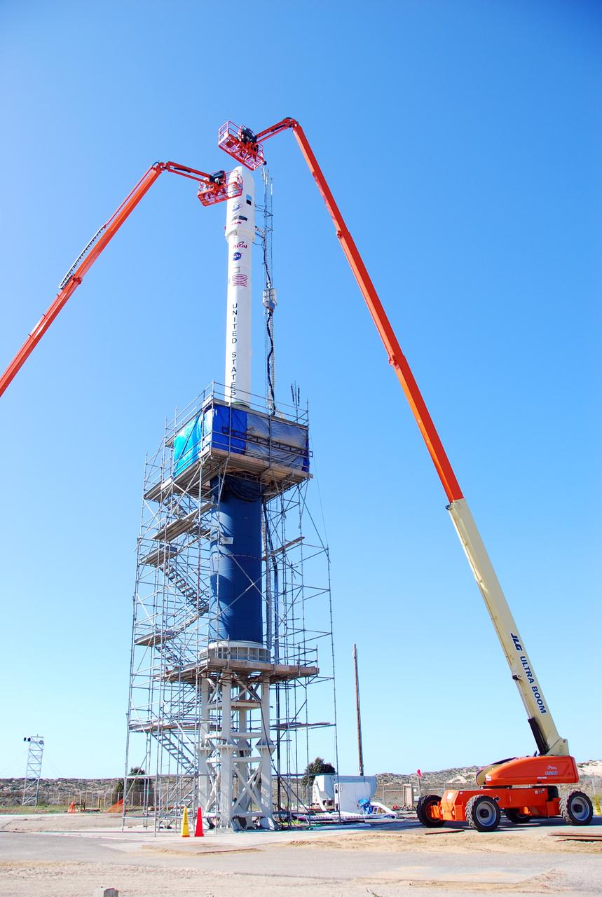 VANDENBERG AIR FORCE BASE, Calif. --  On Launch Complex 576-E at Vandenberg Air Force Base in California, Orbital Sciences Engineer Jose Castillo maneuvers the bucket truck at right into position over the fairing access door on NASA's Orbiting Carbon Observatory, or OCO.  Glenn Weigle of Orbital Satellite Systems Group is on the bucket at left.  Weigle is prepared to move in and inspect the GN2 instrument purge flow. OCO will collect precise global measurements of carbon dioxide (CO2) in the Earth's atmosphere. Scientists will analyze OCO data to improve our understanding of the natural processes and human activities that regulate the abundance and distribution of this important greenhouse gas. OCO is scheduled to launch Feb. 24 aboard an Orbital Sciences' Taurus XL rocket.  Photo credit: NASA/Richard Nielsen, KSC