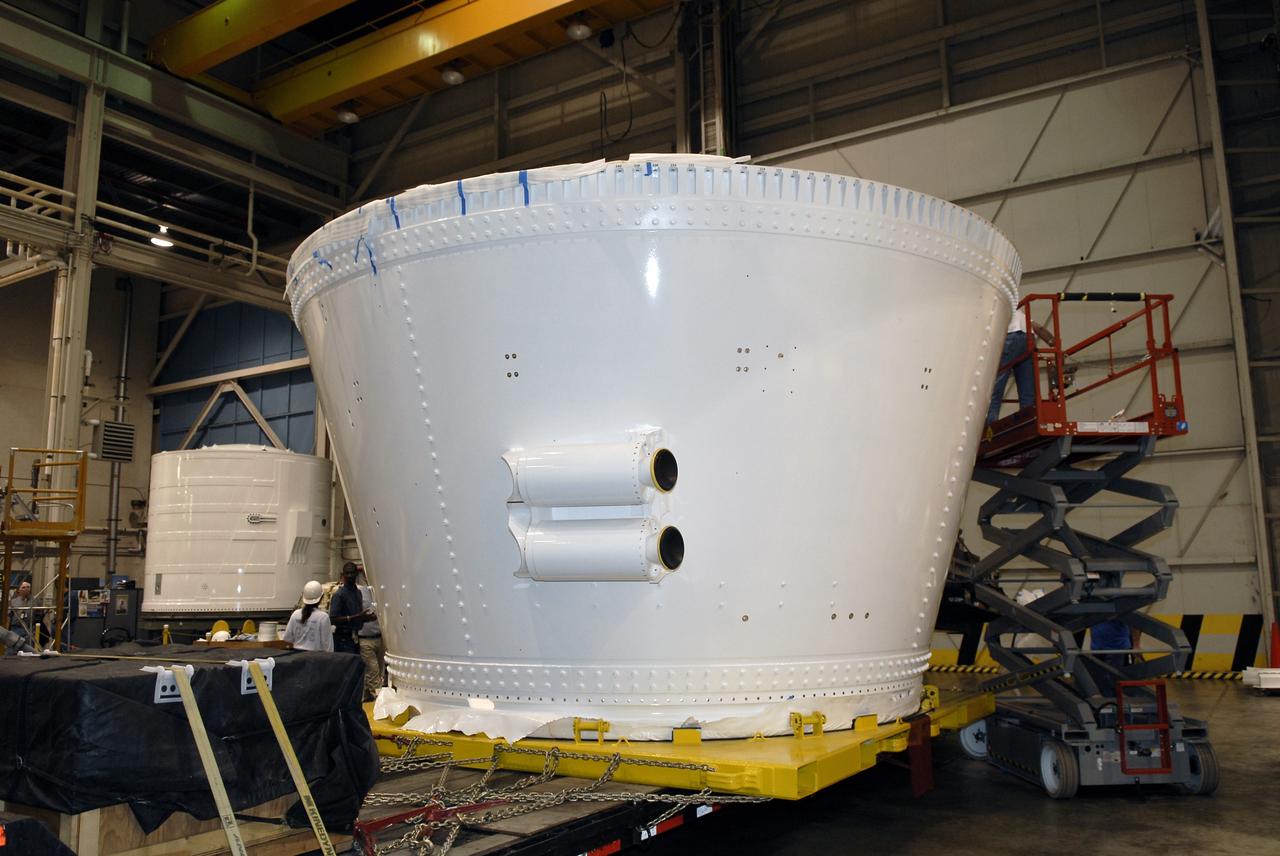 CAPE CANAVERAL, Fla. – In the Assembly and Refurbishment Facility of NASA's Kennedy Space Center, the last newly manufactured section of the Ares I-X test rocket, the frustum, is revealed after removal of the shipping covers.  Resembling a giant funnel, the frustum's function is to transition the primary flight loads from the rocket's upper stage to the first stage. The frustum is located between the forward skirt extension and the upper stage of the Ares I-X. Weighing in at approximately 13,000 pounds, the 10-foot-long section is composed of two aluminum rings attached to a truncated conic section. The large diameter of the cone is 18 feet and the small diameter is 12 feet. The cone is 1.25 inches thick. The frustum will be integrated with the forward skirt and forward skirt extension, which already are in the Assembly and Refurbishment Facility. That will complete the forward assembly. The assembly then will be moved to the Vehicle Assembly Building for stacking operations, which are scheduled to begin in April. Manufactured by Major Tool and Machine Inc. in Indiana under a subcontract with Alliant Techsystems Inc., or ATK, the Ares I-X is targeted to launch in the summer of 2009. The flight will provide NASA with an early opportunity to test and prove hardware, facilities and ground operations associated with the Ares I launch vehicle. The flight test also will bring NASA a step closer to its exploration goals of sending humans to the moon and destinations beyond.  Photo credit: NASA/Kim Shiflett