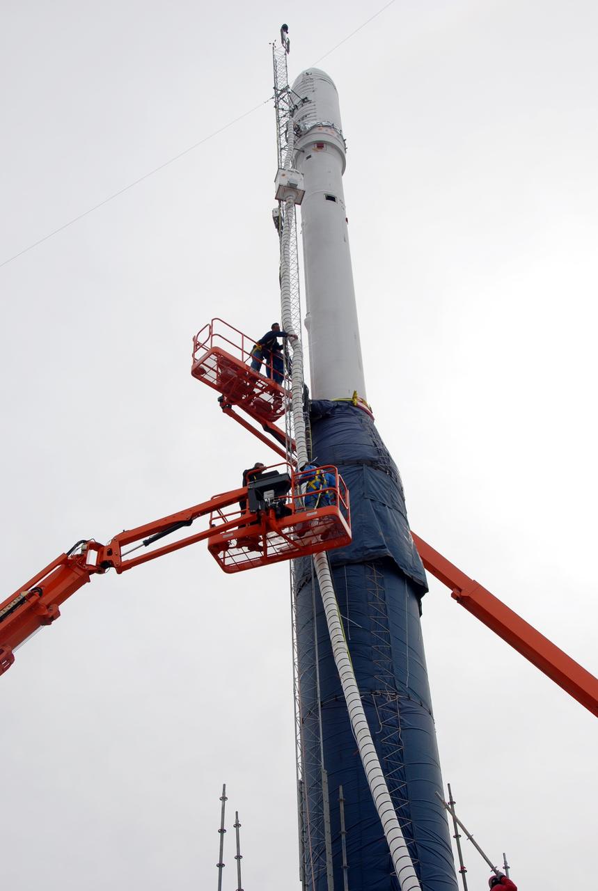 VANDENBERG AIR FORCE BASE, Calif. -- On Launch Complex 576-E at Vandenberg Air Force Base in California, workers in the bucket trucks are securing the fairing ducting, GN2 purge line, and cable harnesses to the umbilical mast attached to Orbital Sciences' Taurus XL rocket.  Atop the rocket is NASA's Orbiting Carbon Observatory, or OCO, which is scheduled to launch Feb. 24 from Vandenberg. The spacecraft will collect precise global measurements of carbon dioxide (CO2) in the Earth's atmosphere. Scientists will analyze OCO data to improve our understanding of the natural processes and human activities that regulate the abundance and distribution of this important greenhouse gas.  Photo credit: NASA/Richard Nielsen, VAFB