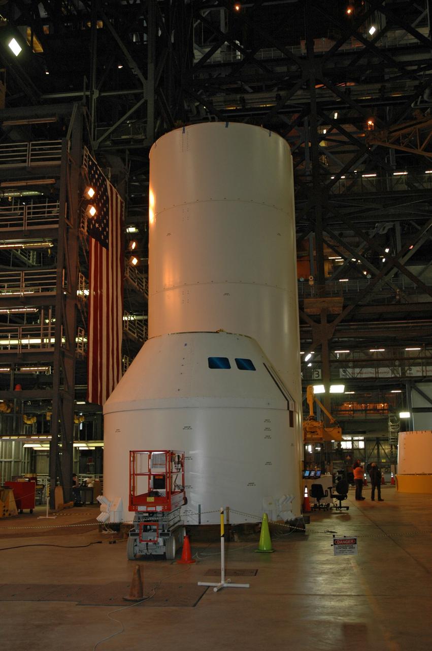 CAPE CANAVERAL, Fla. – In high bay 4 of the Vehicle Assembly Building at NASA's Kennedy Space Center in Florida, the Ares I-X crew/service module simulator (foreground) will be moved following a fit check.   Ares I-X is the test flight for the Ares I.   The I-X flight will provide NASA an early opportunity to test and prove hardware, facilities and ground operations associated with Ares I. The launch of the 327-foot-tall, full-scale Ares I-X, targeted for July 2009, will be the first in a series of unpiloted rocket launches from Kennedy. When fully developed, the 16-foot diameter crew module will furnish living space and reentry protection for the astronauts.  Photo credit: NASA/Tim Jacobs